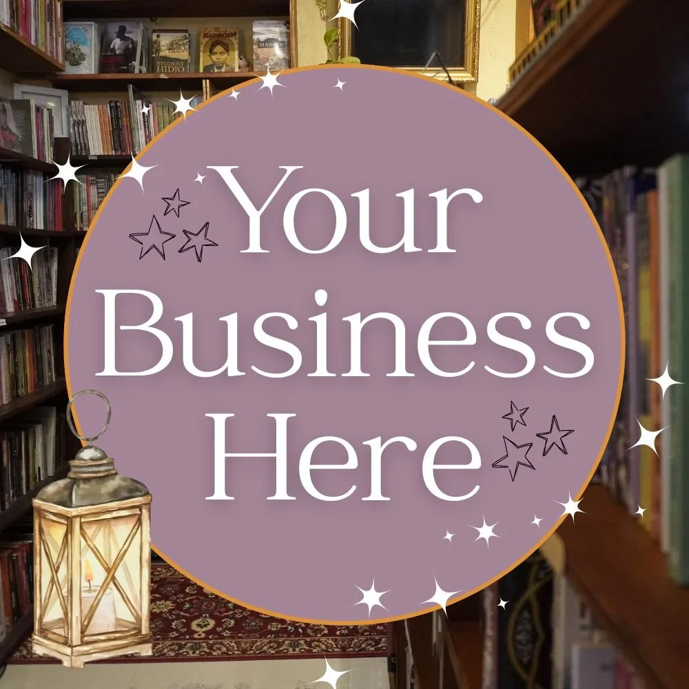Sign with the text 'Your Business Here' in a bookstore or library setting, with bookshelves, a lantern, and star decorations.