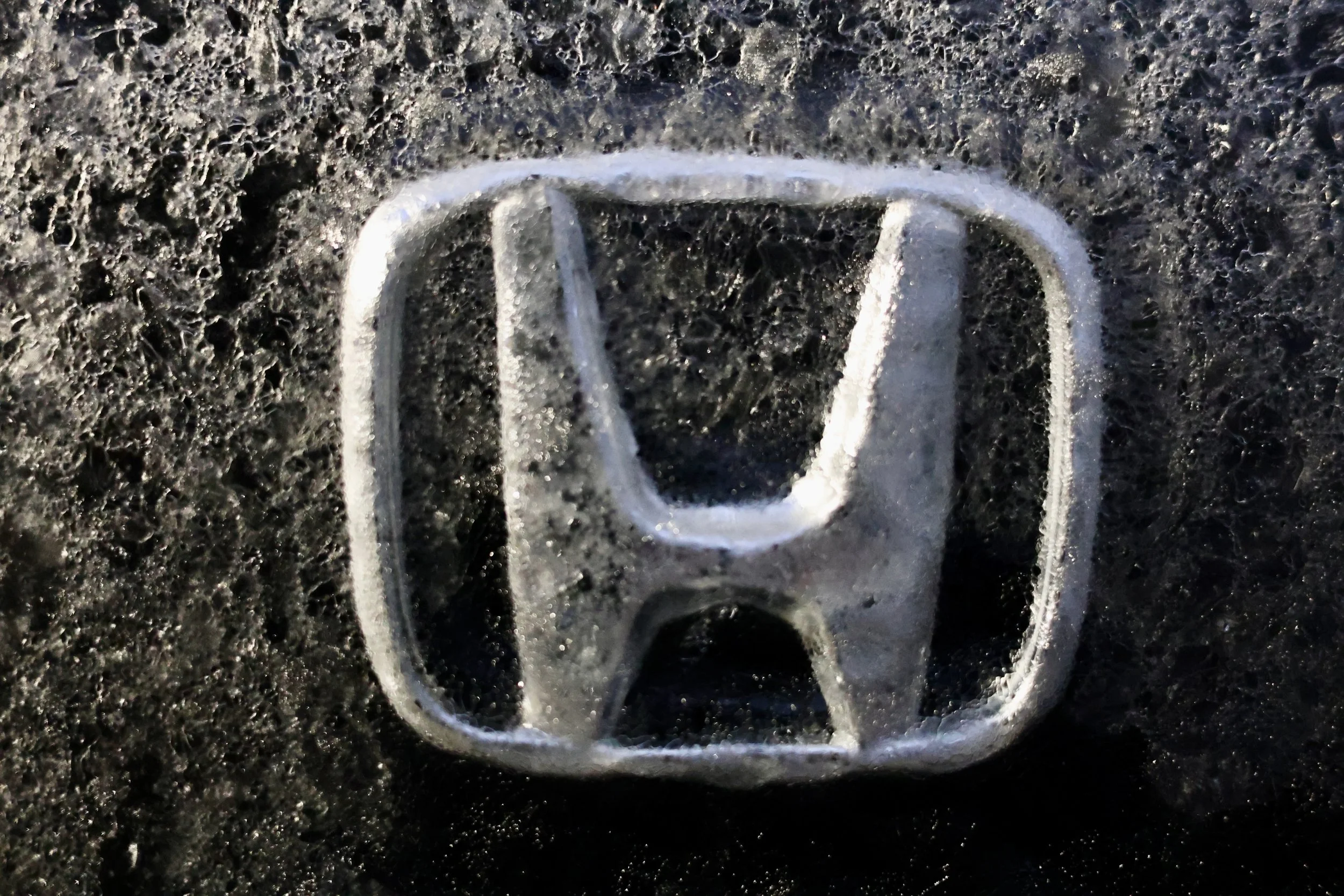 Close-up of a silver metallic soda can tab on a dark, textured surface.
