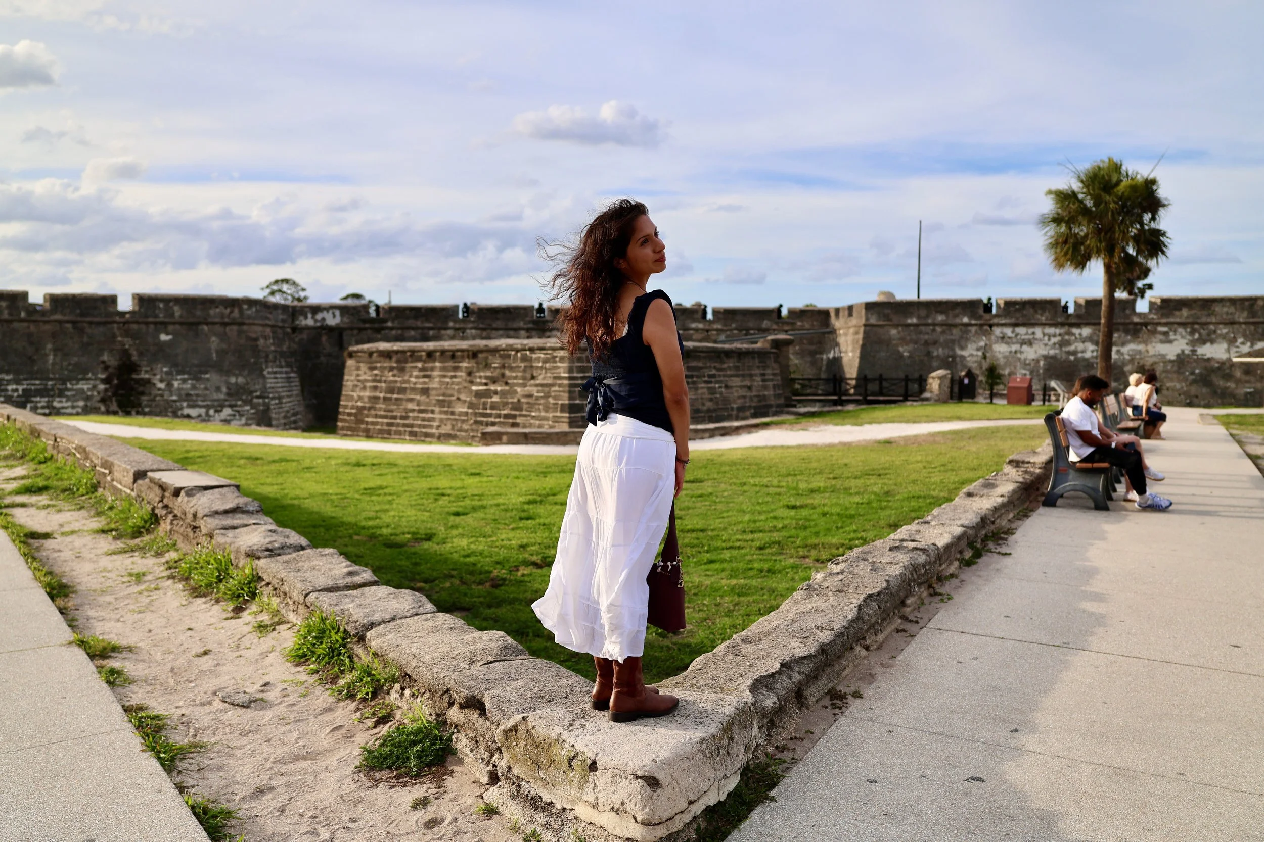 A young woman looks out to her right in front of an old Spanish fort.