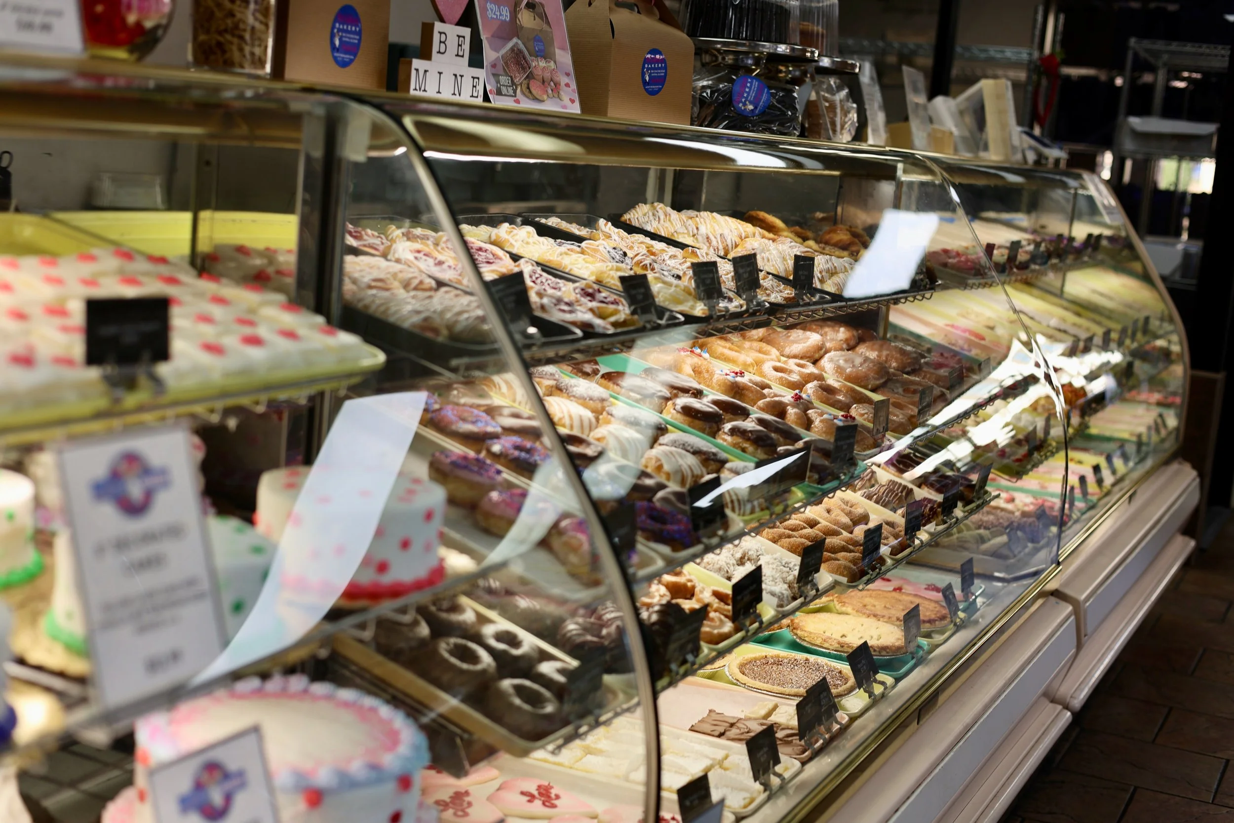 Display case filled with assorted baked goods including cakes, pastries, and donuts at a Smyrna, Georgia bakery.