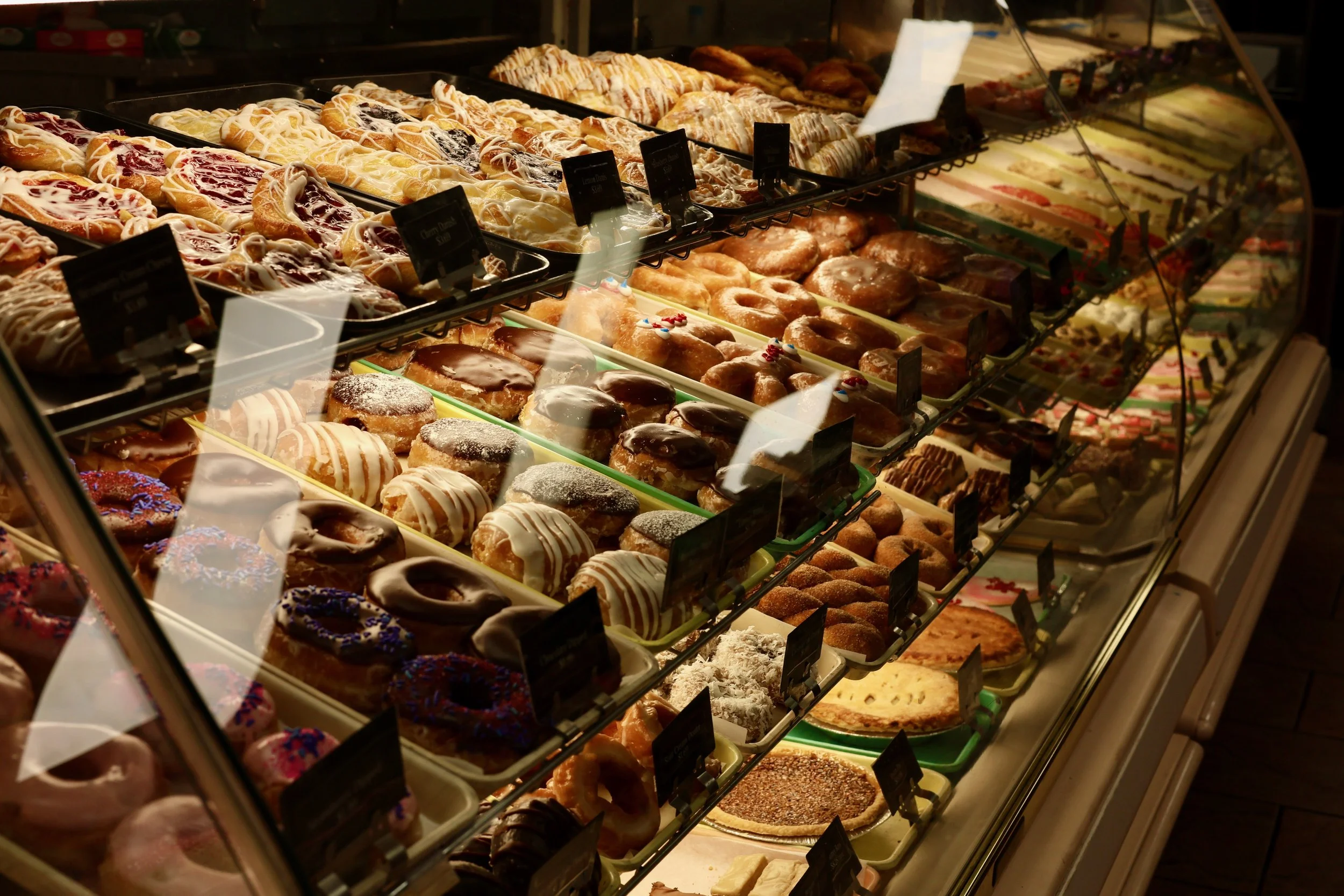 Display case filled with various donuts, pastries, and baked goods.
