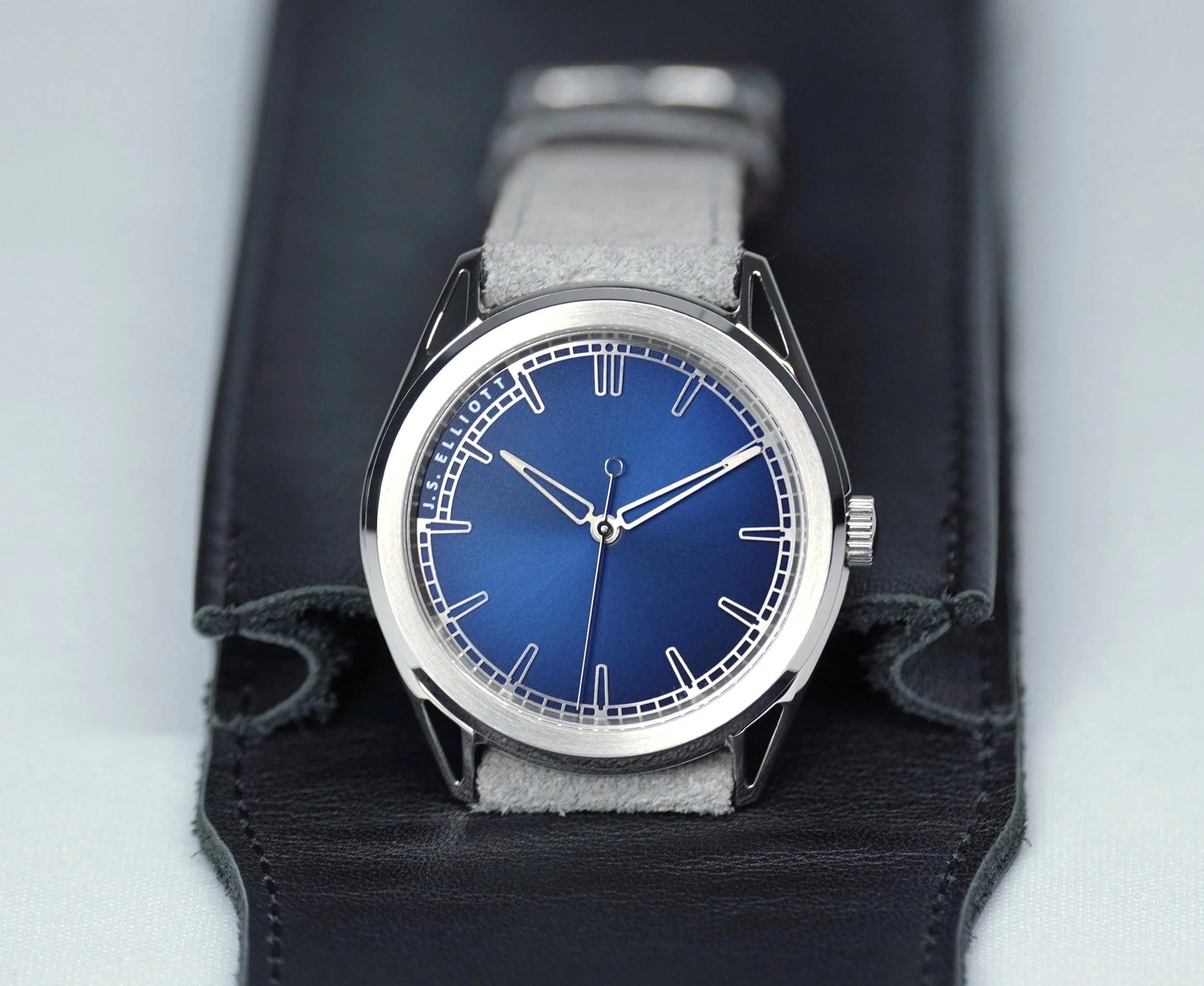A wristwatch with a blue dial and silver bezel, placed on a black display background.