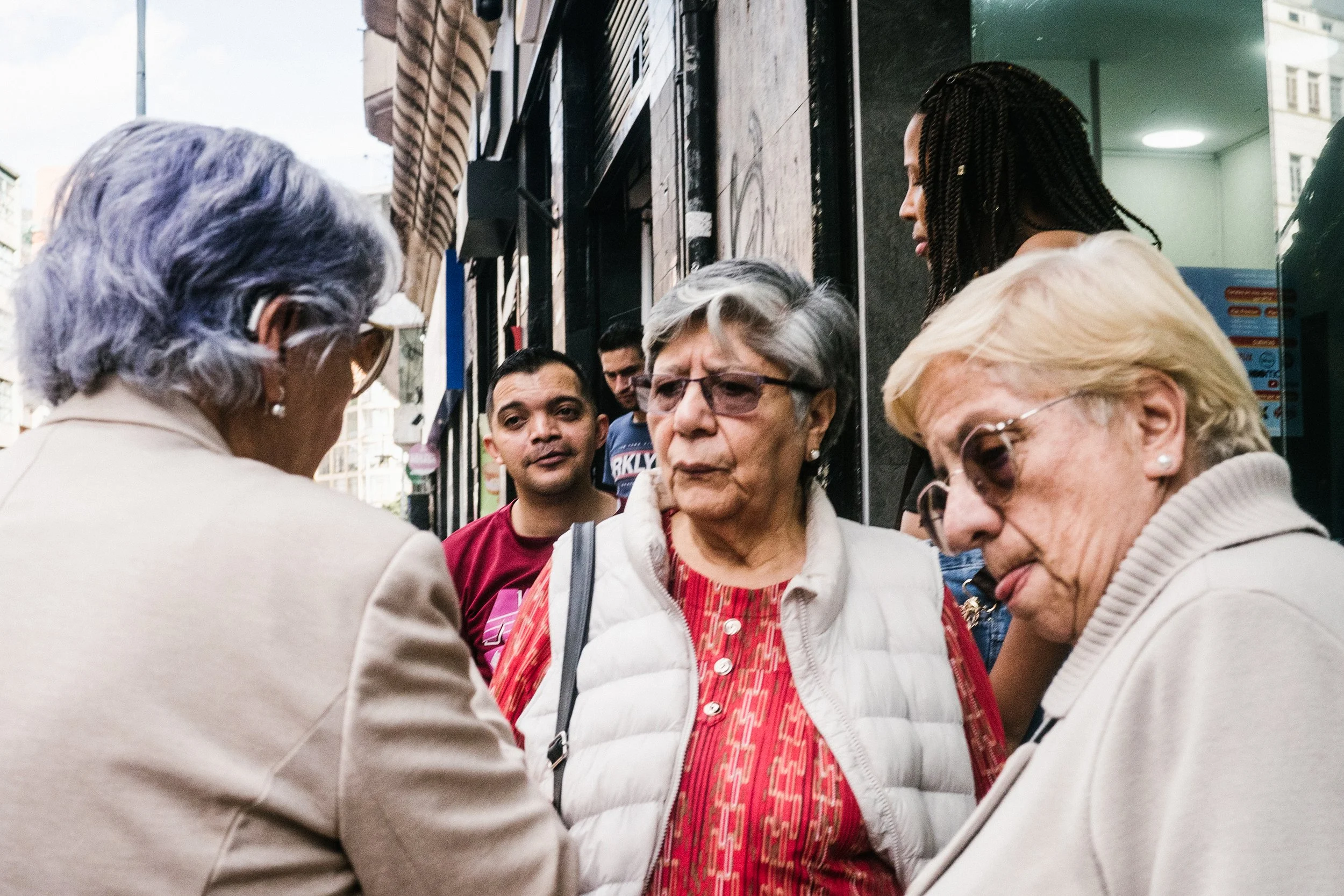 Grupo de personas de diferentes edades en una calle, participando en una conversación o en una interacción social.