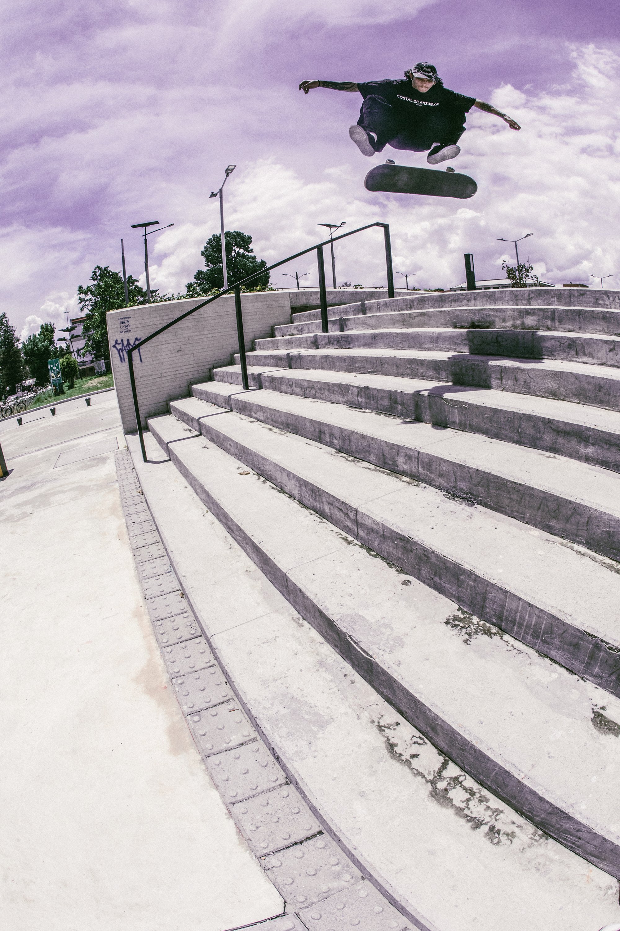 Una persona saltando sobre un conjunto de escaleras en un parque, haciendo trucos con una patineta.
