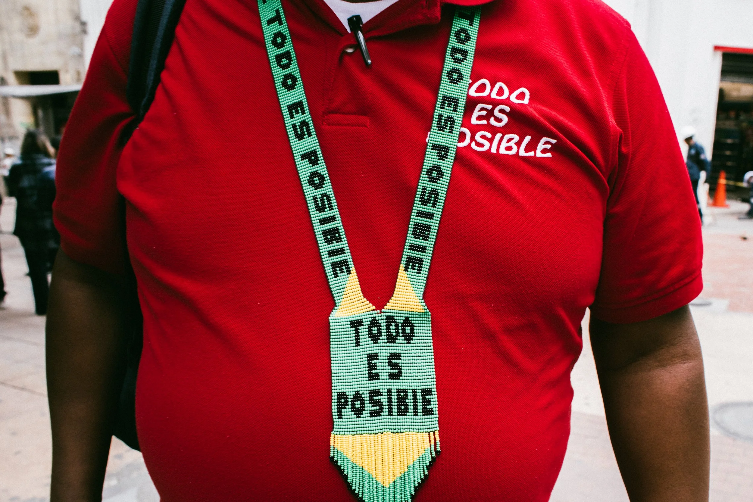 Persona con camiseta roja y un collar de medalla colgado en el cuello, en un espacio urbano.