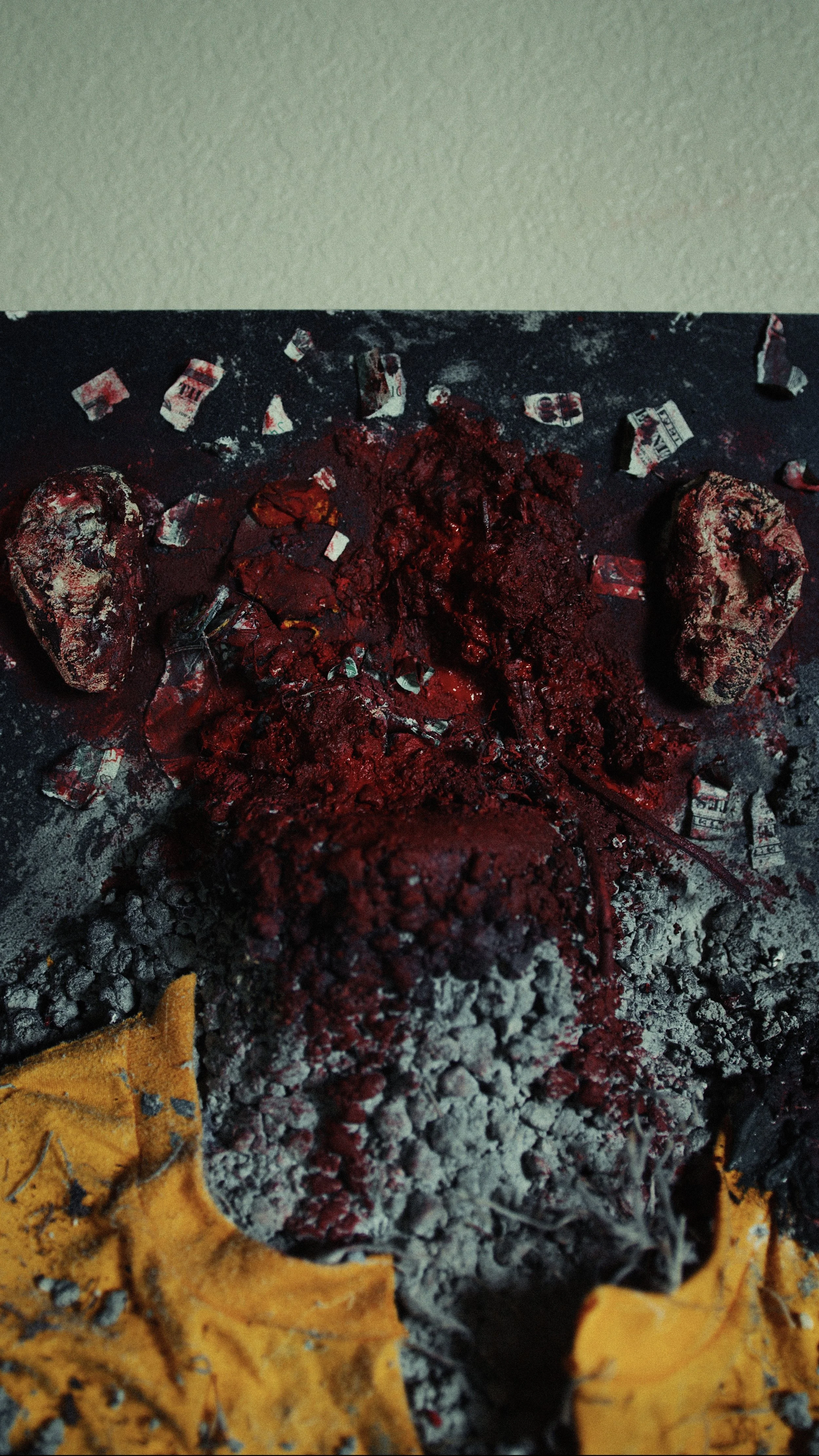 Close-up of burnt ashes, charred wood, and crumpled paper next to yellow leaves.