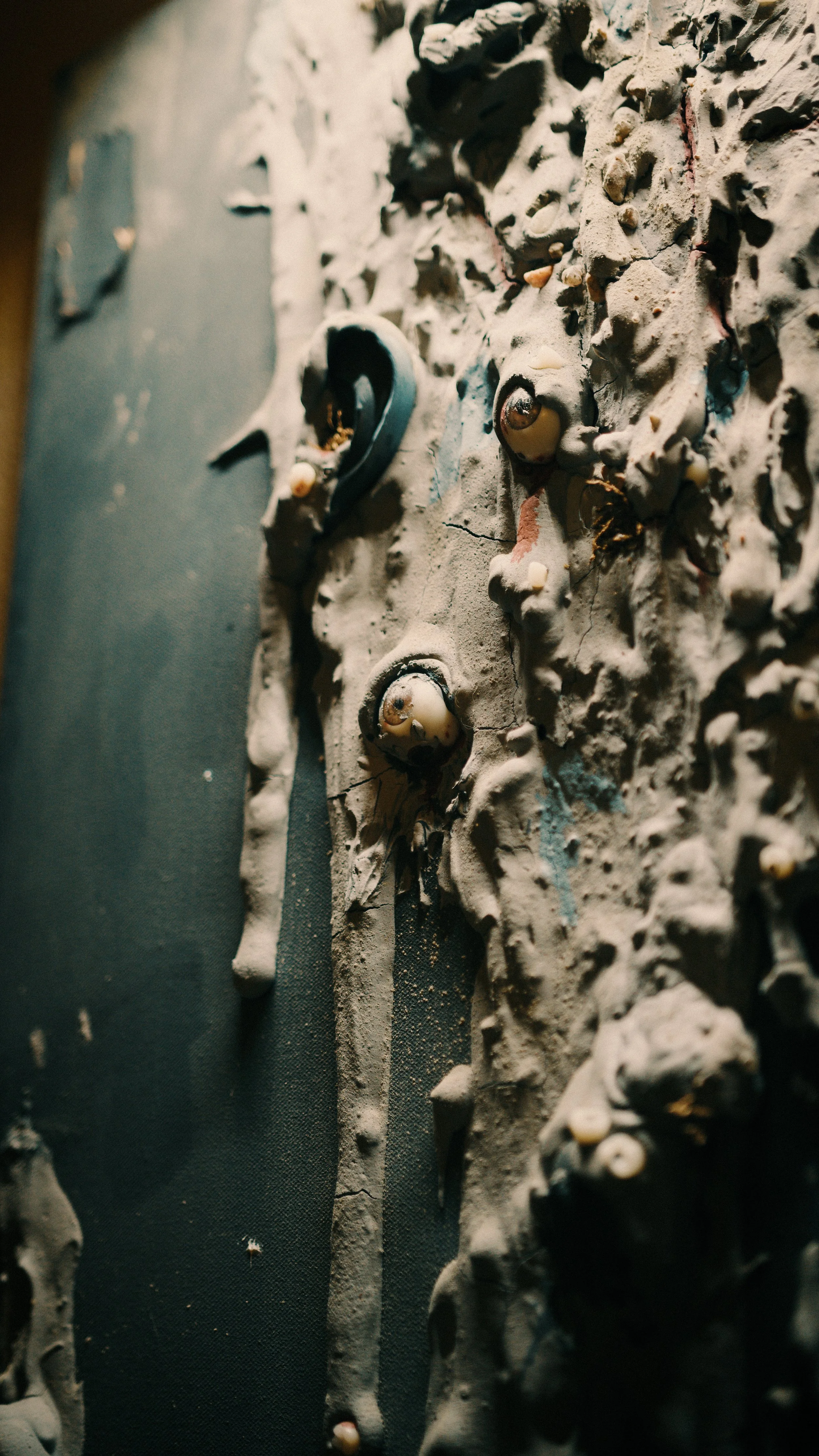 Close-up view of a textured rock climbing wall with small holds and cracks, partially lit with shadows.