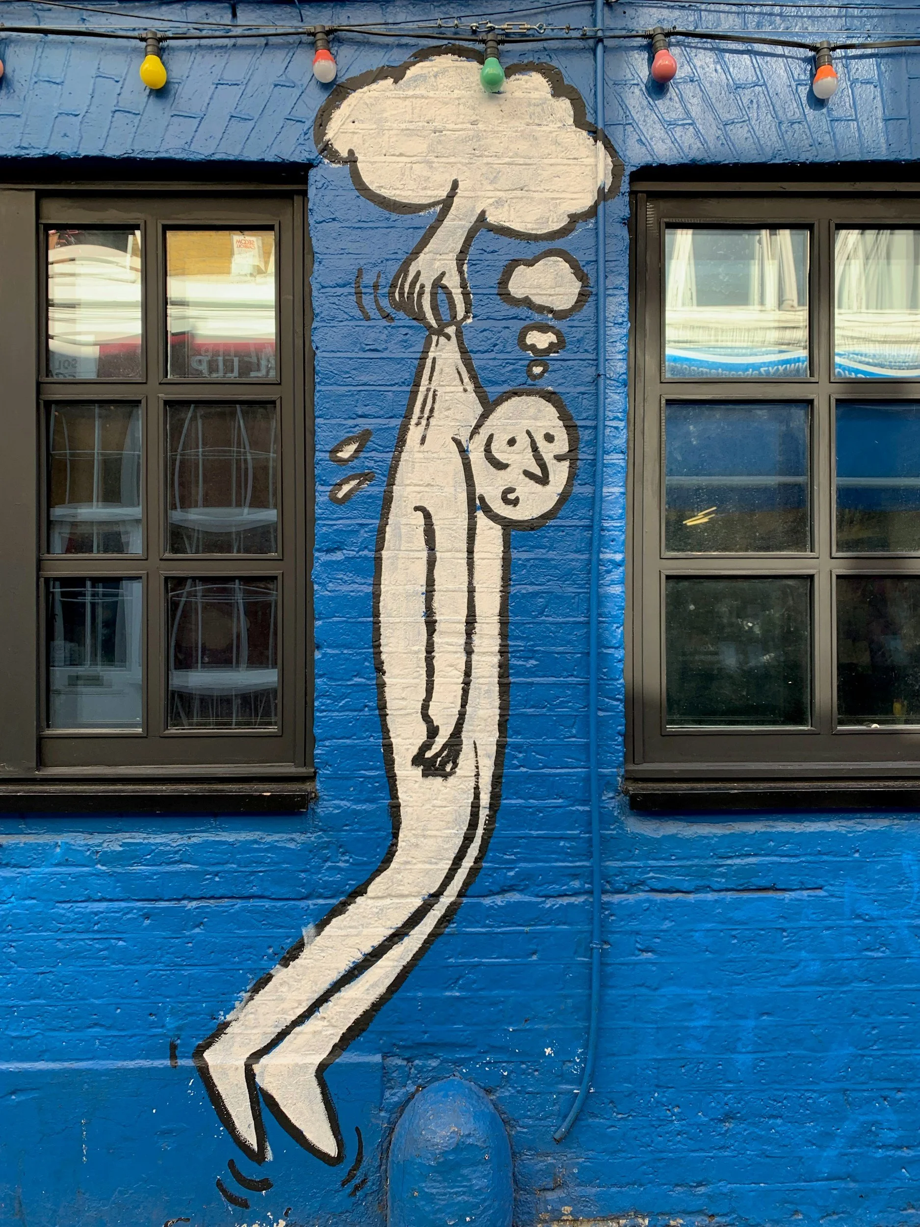 Graffiti of someone hanging from a cloud with a hand