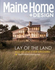 Cover of Maine Home + Design magazine, June 2015 issue, featuring a large modern house surrounded by trees and grass, with the title 'Lay of the Land' and the subtitle 'Houses that Speak to Their Surroundings'.