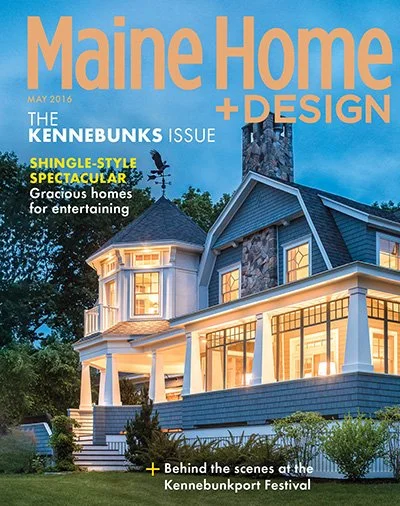 The cover of Maine Home + Design magazine, May 2016 issue, features a large, elegant blue and white house illuminated at twilight with trees and shrubs nearby.