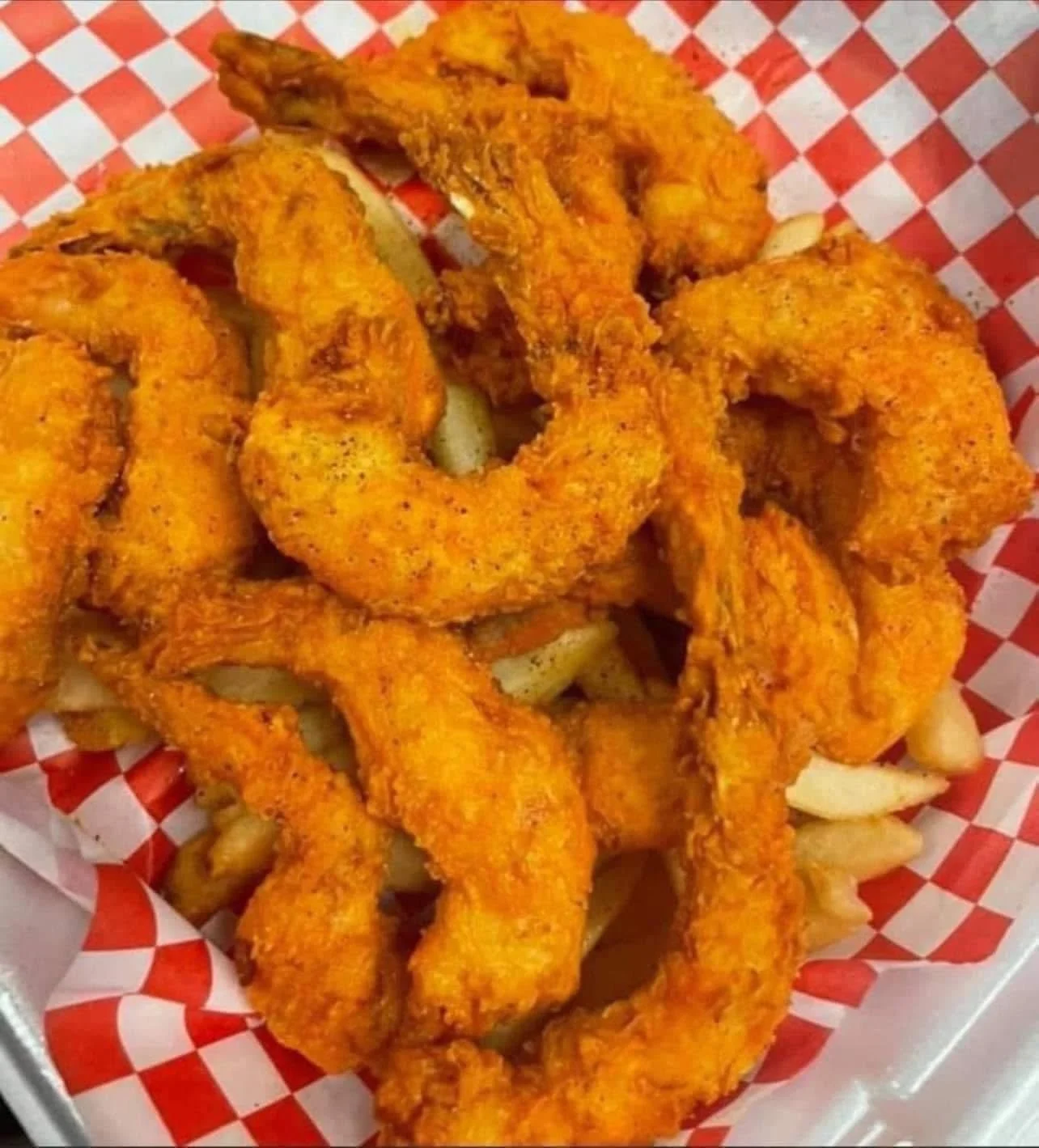 Fried shrimp with seasoned coating on a paper-lined basket.