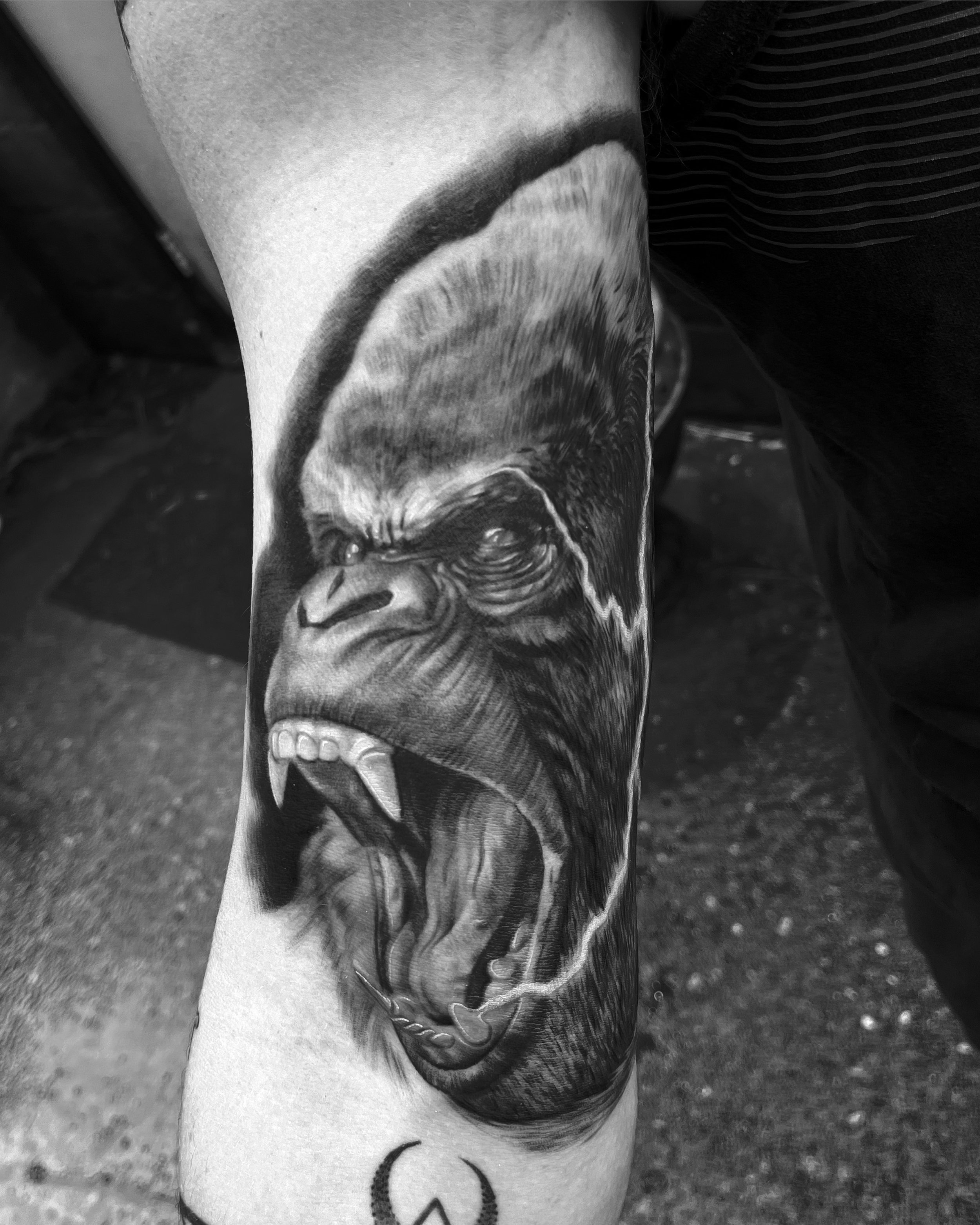Close-up of a tattoo on a person's arm featuring a realistic depiction of a gorilla's face by Jesse Smith Tattoo Artist at Bethel Park, PA.