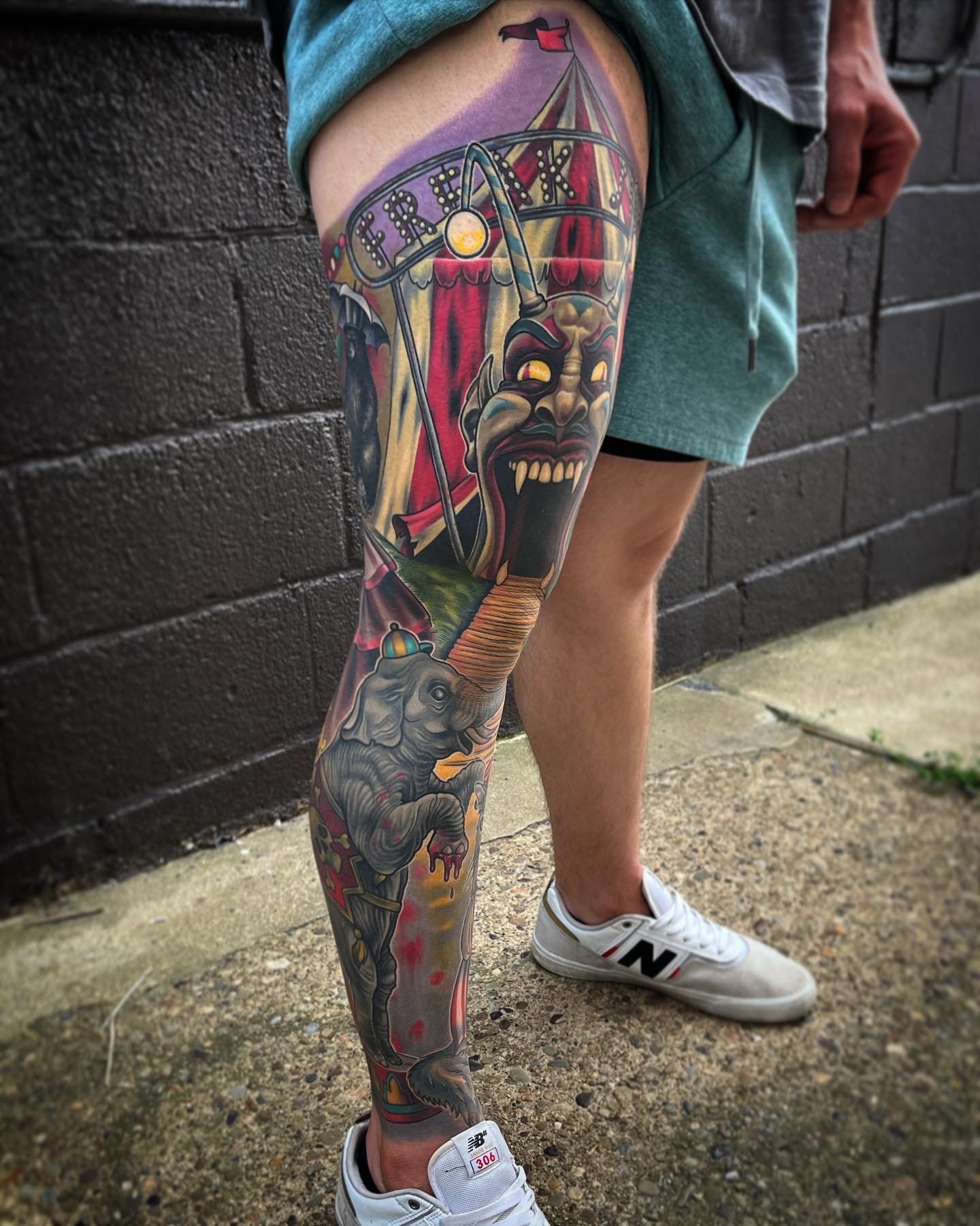 A custom full leg sleeve featuring a clown in a carnival setting, tiger, elephant, and colorful background by Jesse Smith at Human Production Gallery.