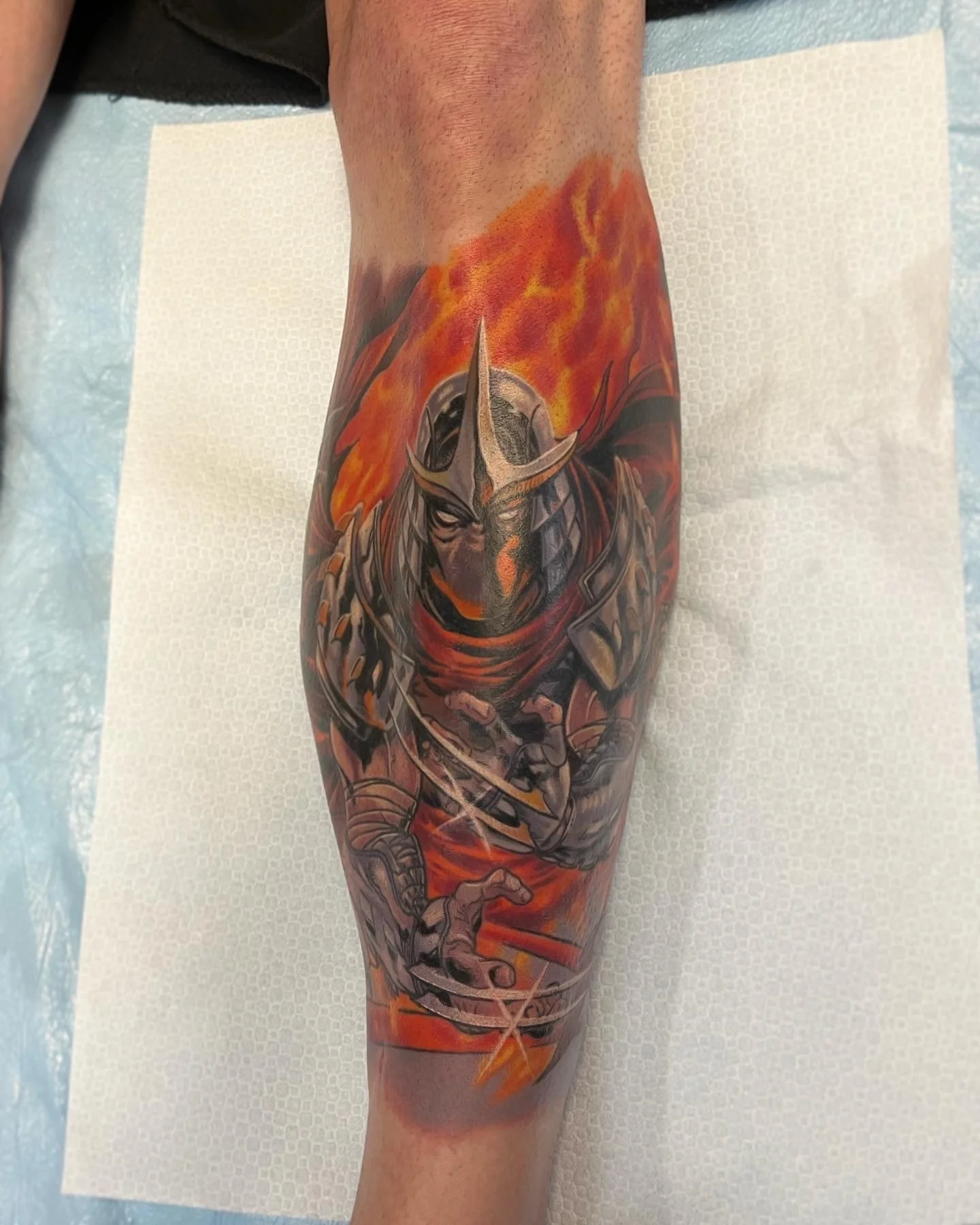 Colorful tattoo of a wolf on a person's arm, with flames in the background.
