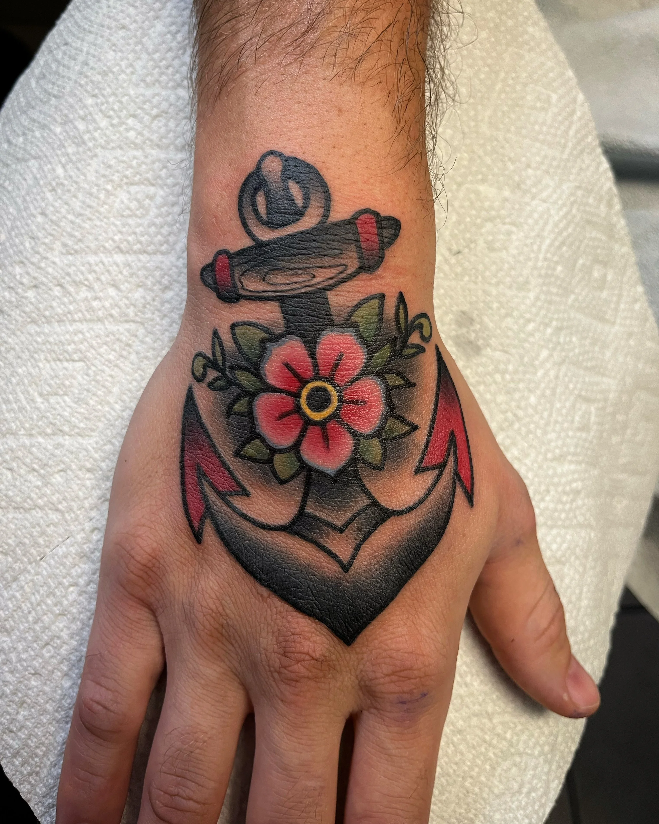 Traditional hand tattoos featuring anchor with pink flower by Jesse Smith tattoo artist in the South Hills of Pittsburgh.