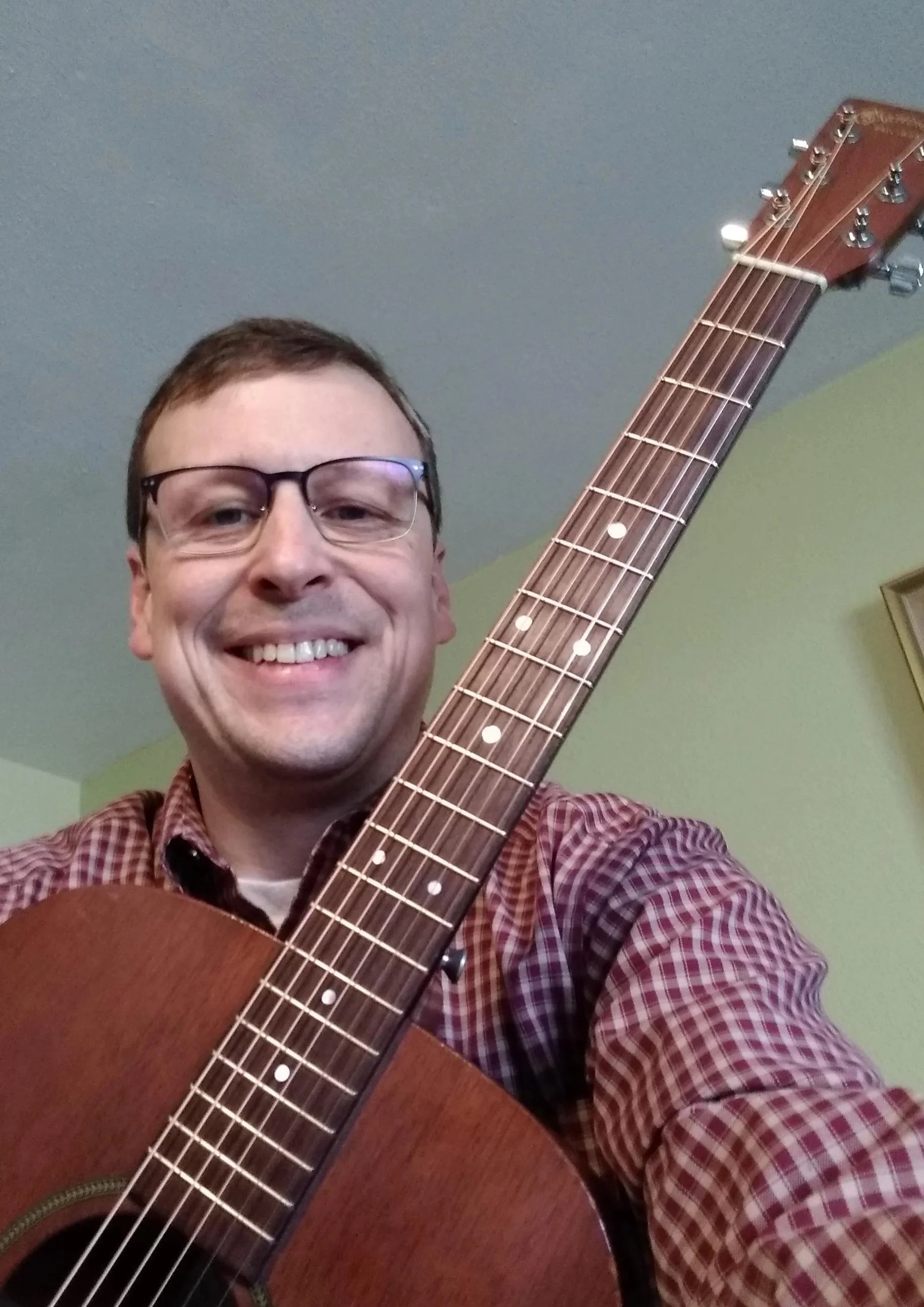 Michael Straight with his guitar in his guitar lesson studio.