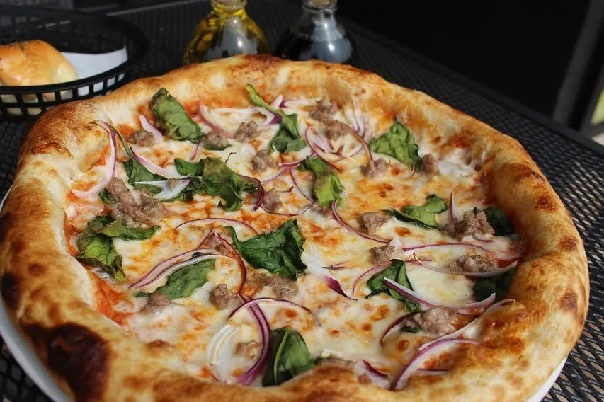 Pizza con queso, carne, cebolla morada y hojas verdes