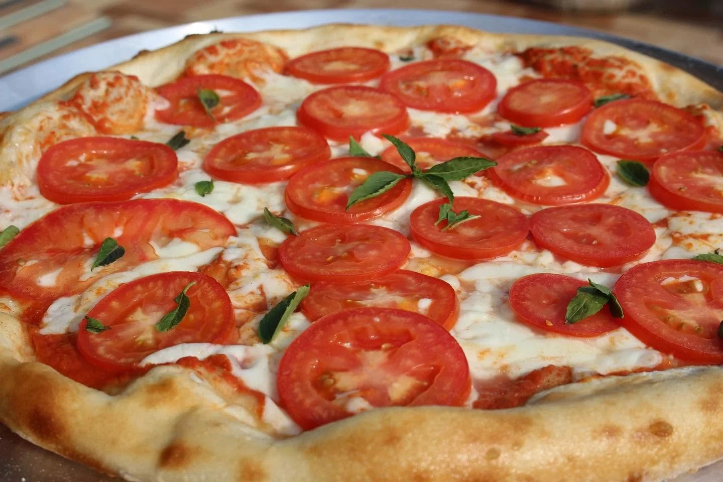 Pizza con tomate, queso mozzarella y albahaca fresca.
