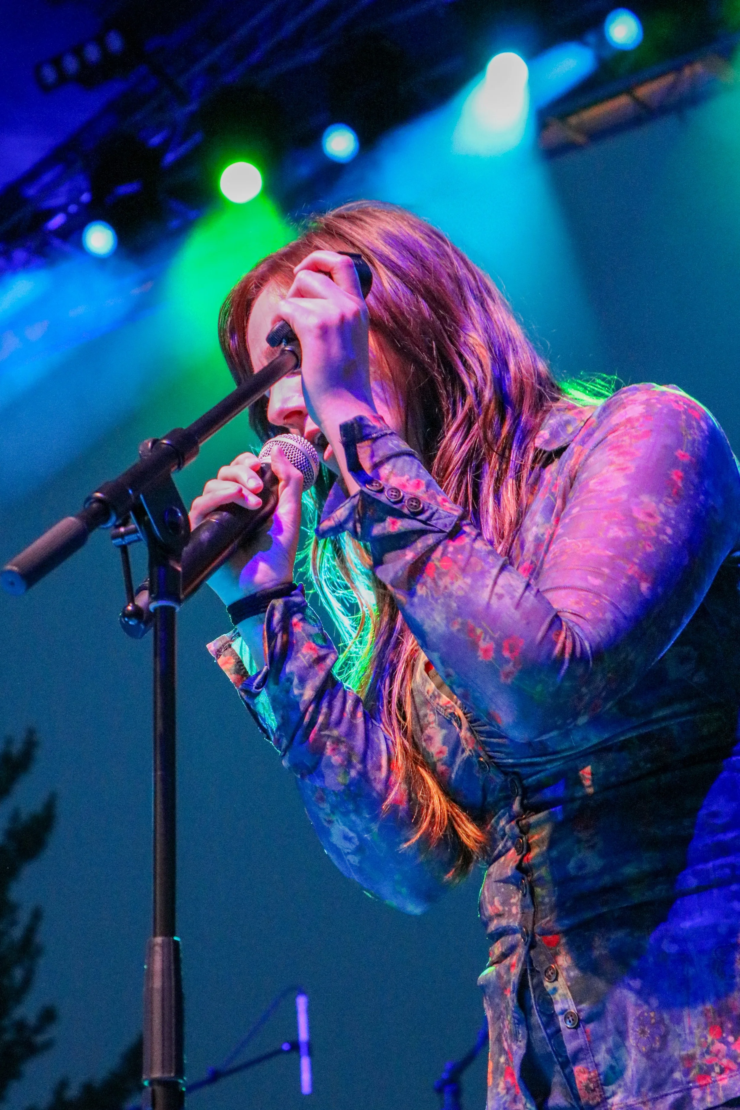 A member of The Groove Merchants sings into a microphone under neon lights