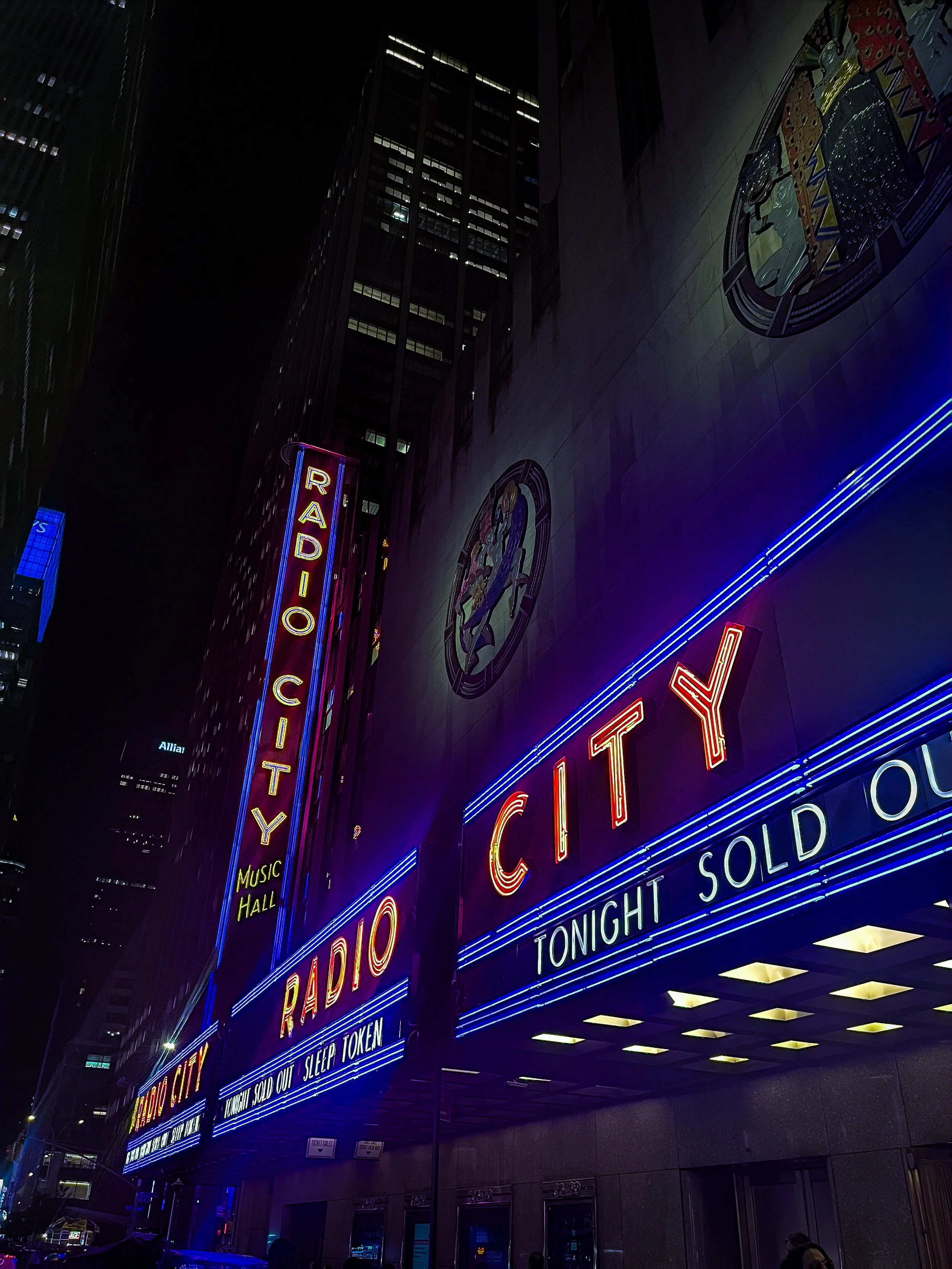 Radio City Music Hall marquee in New York City at night, illuminated with neon lights advertising a Sleep Token sold-out show