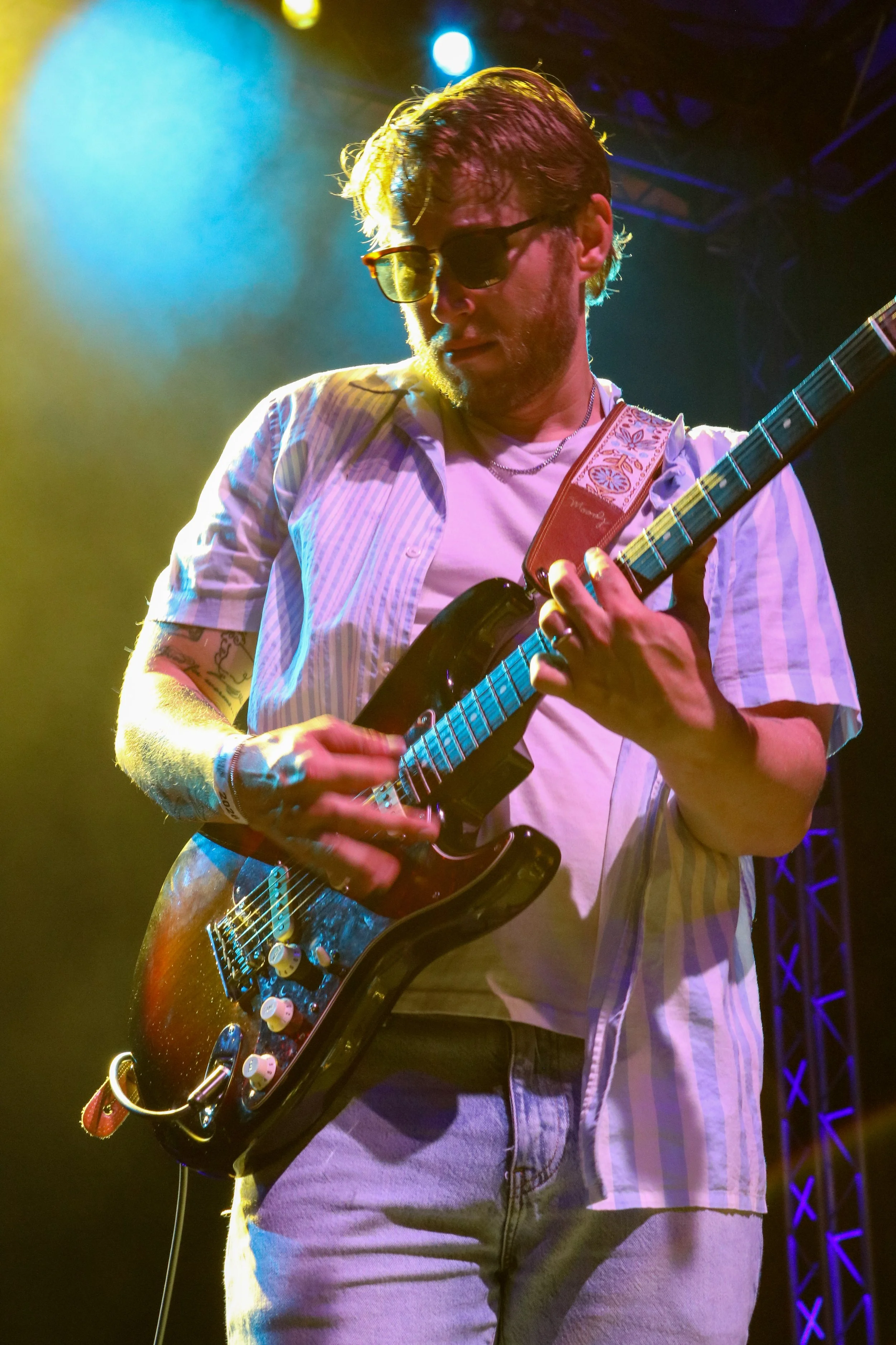 Tye of The Groove Merchants plays guitar under neon lights and fog