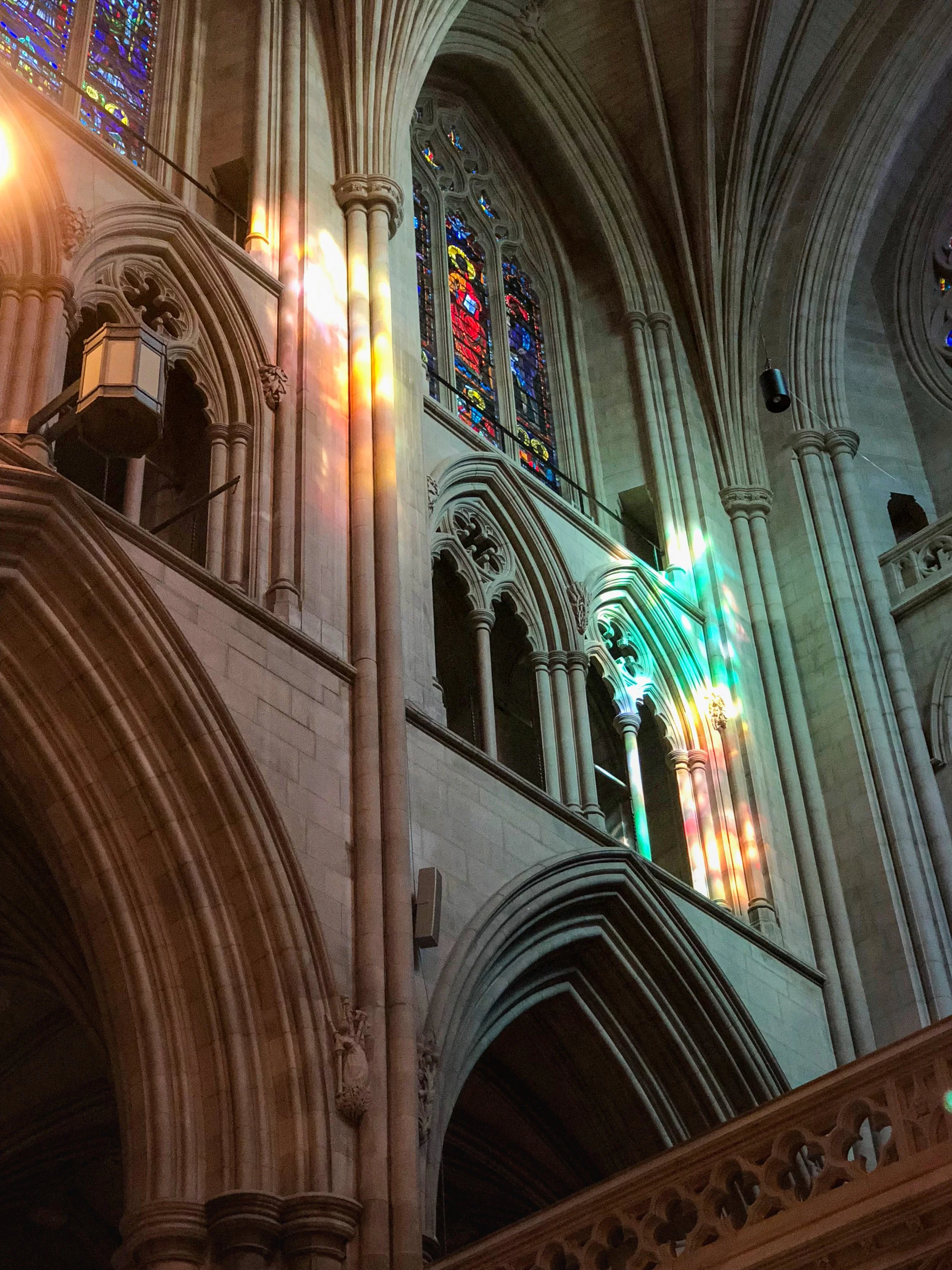 Rainbow-colored light shining through stained glass on the interior walls of Washington National Cathedral