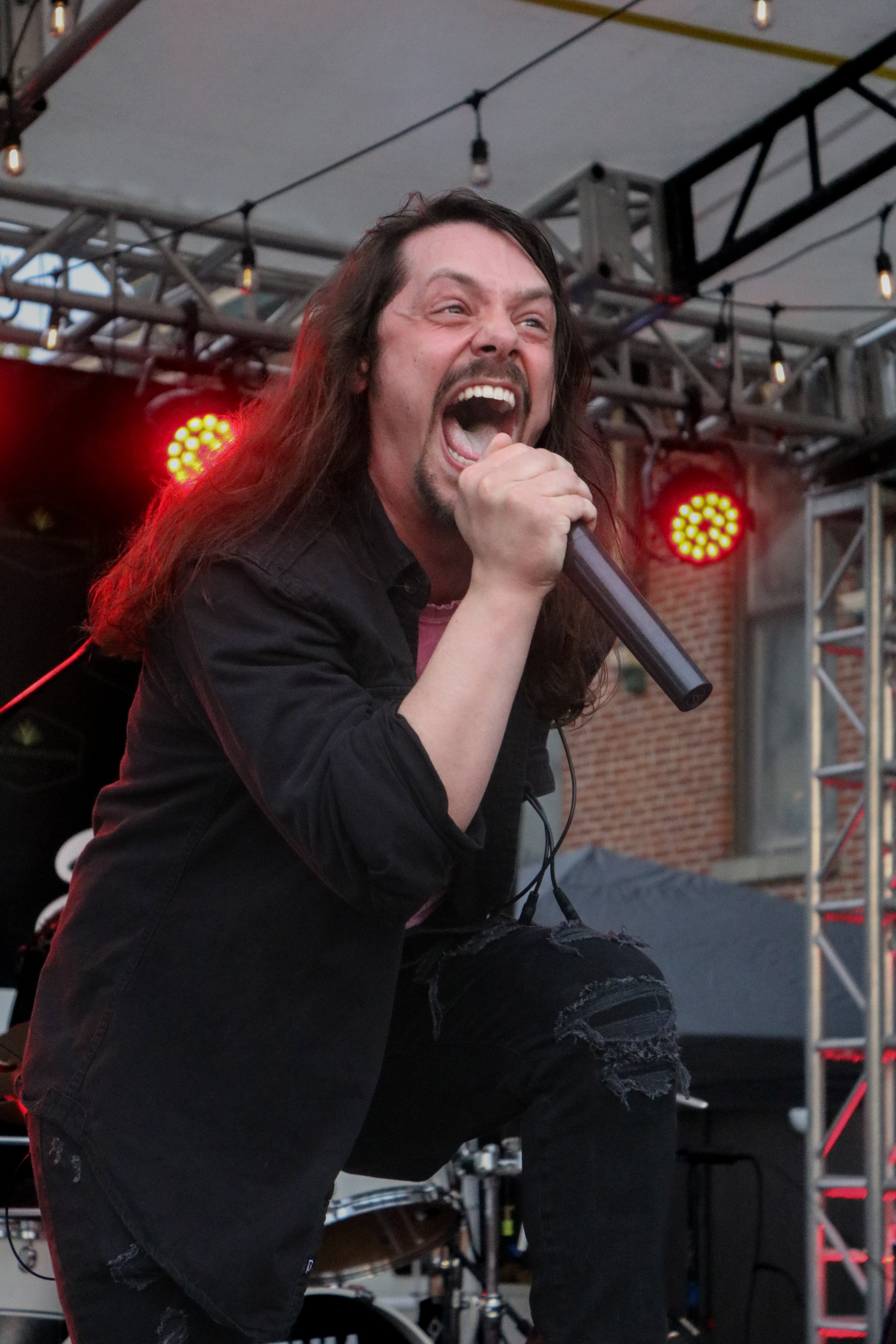 Nolan of Kvrma screams into a microphone during a live performance
