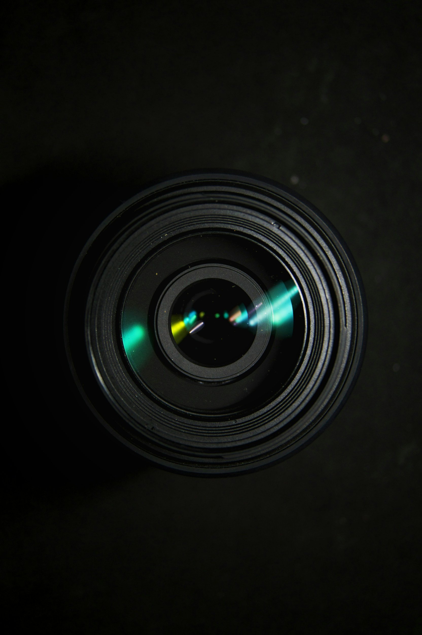 Close-up of a camera lens reflecting colorful lights against a black background.
