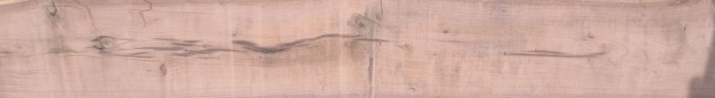 Close-up of a light-colored wooden surface with visible grain and knots.