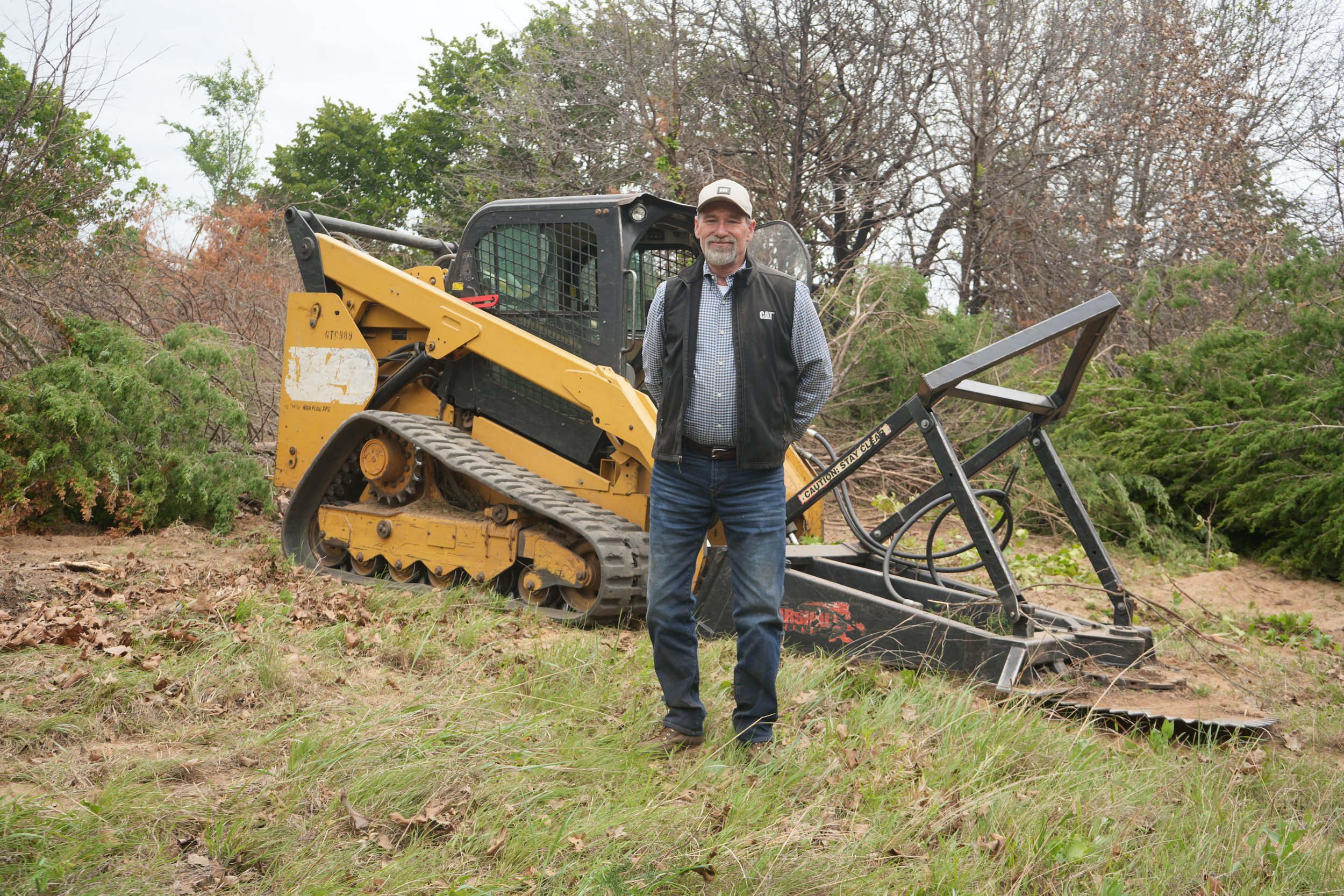 Travis Anglin, owner of Klear Kutt, standing in front of the 299D caterpillar skidsteer with our marshalll saw attachment