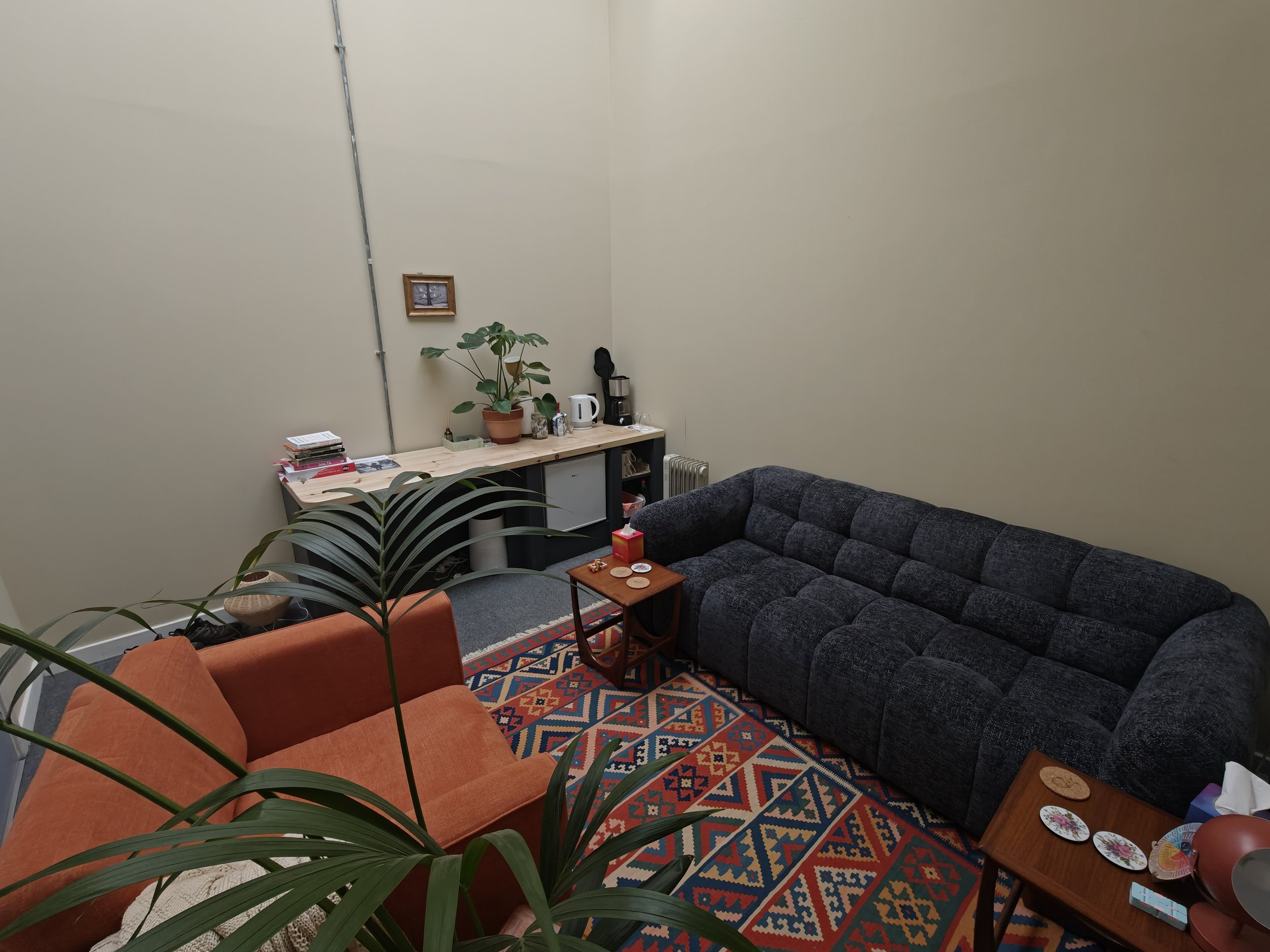 The counselling space in the Stockport area, with a sofa, armchair and plants.