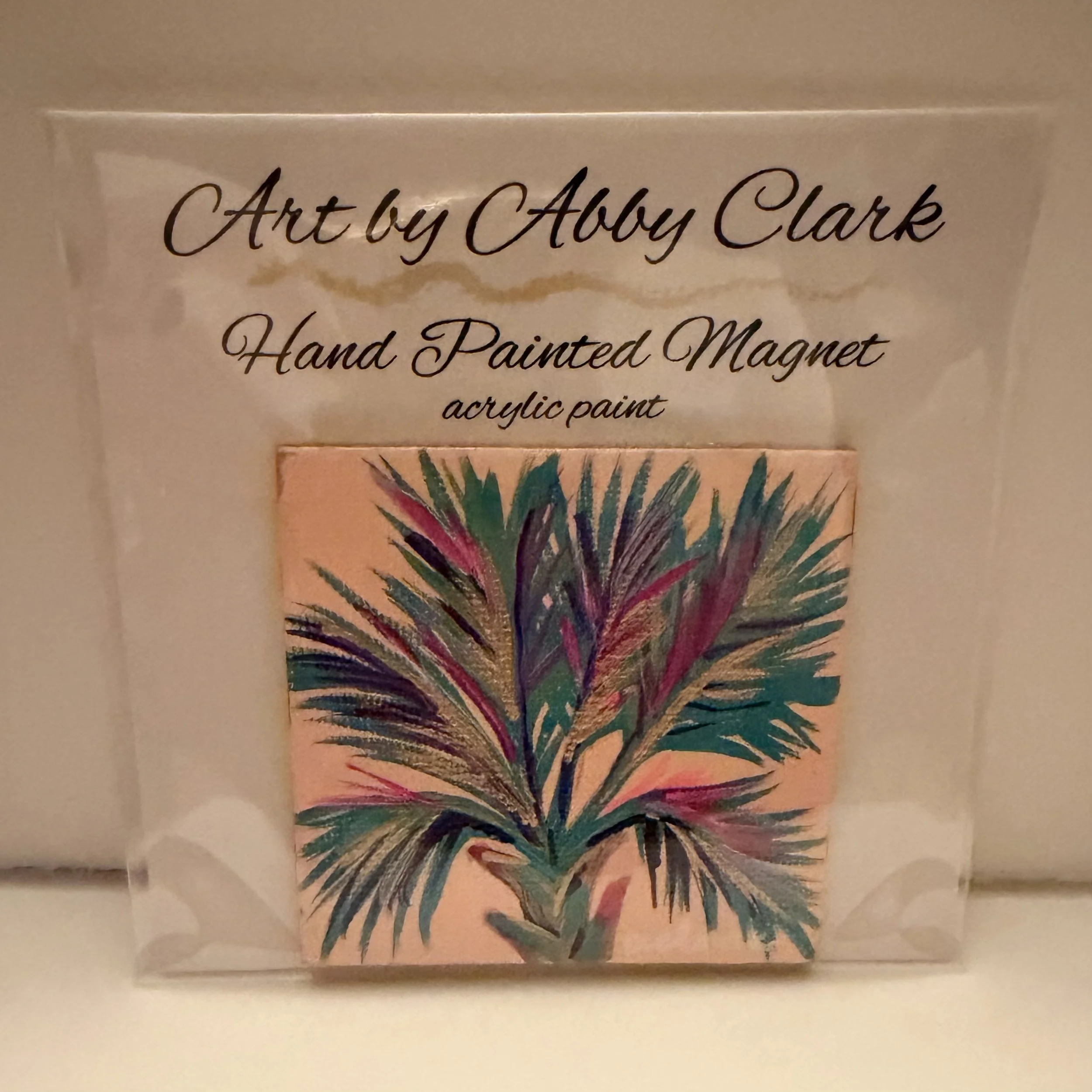 Colorful palmetto fronds in teal, green, magenta and gold on a peach mini canvas magnet by Abby Clark