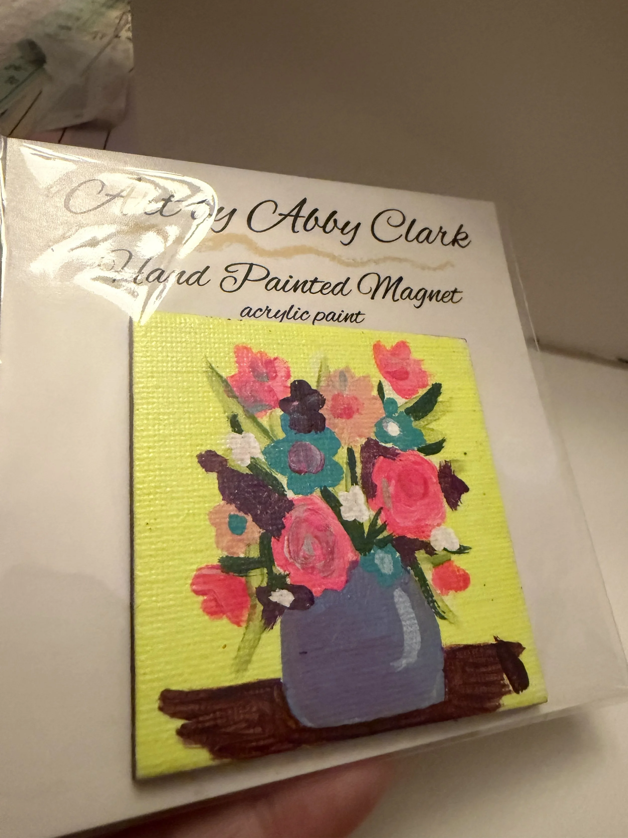 Mini floral magnet with a lavender vase and bright yellow background, painted by Abby Clark