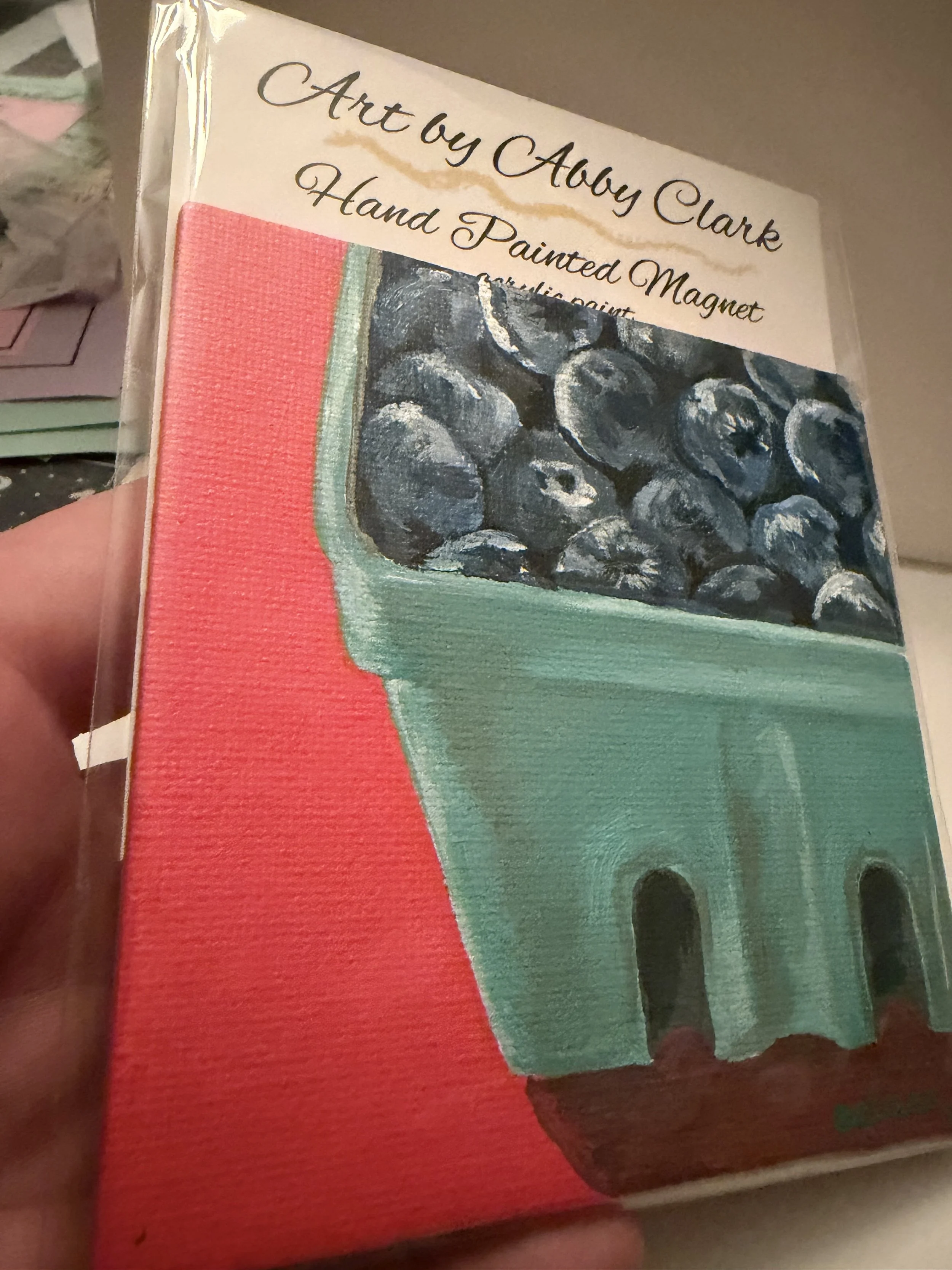 Angled close-up of the blueberry basket canvas magnet, showing painted berries and the textured teal basket