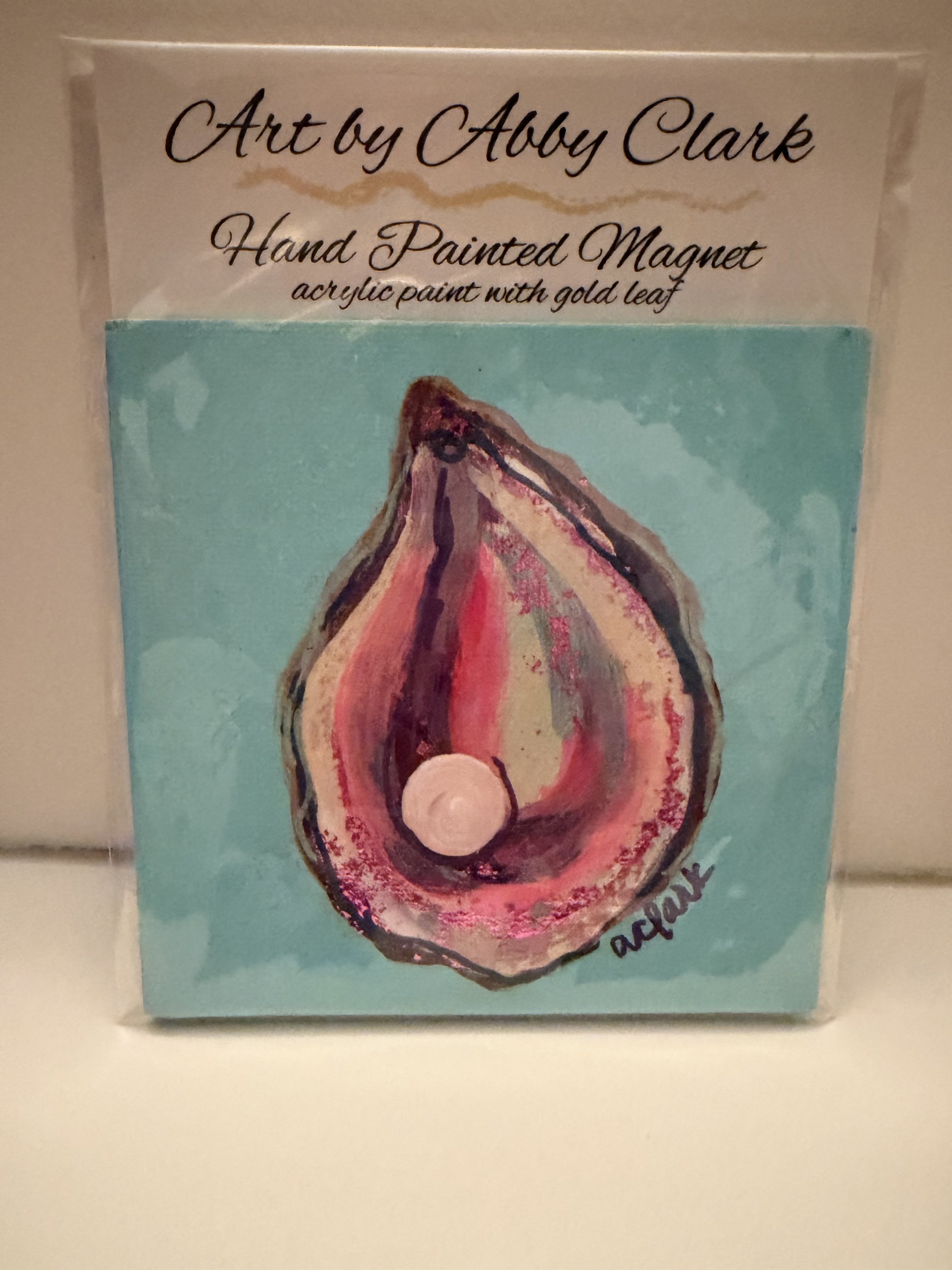 Hand-painted oyster on a turquoise 4 by 4 inch canvas magnet by Abby Clark, with pink and coral shell colors and a raised pearl