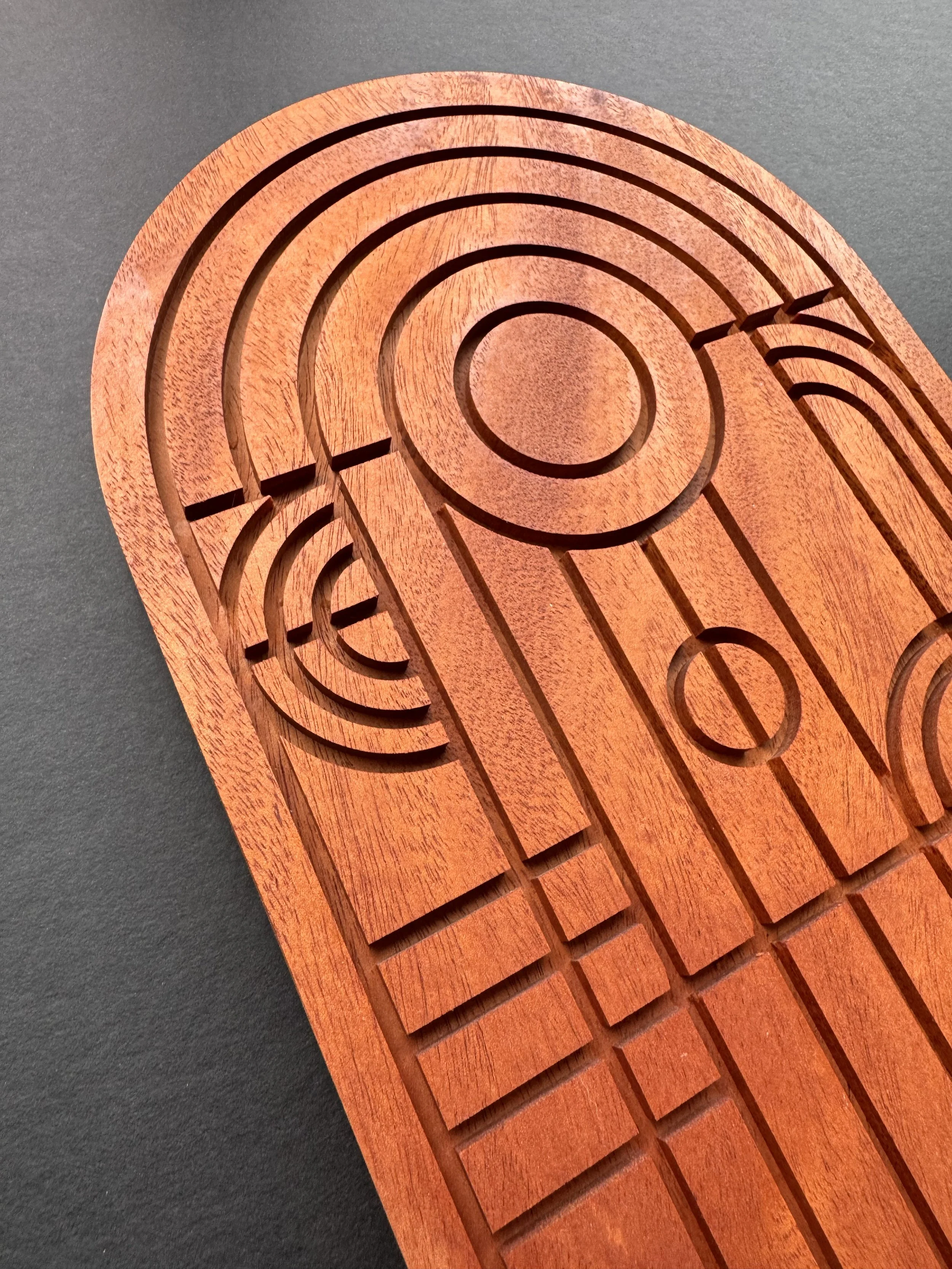 A wooden spiral-shaped, symetrical designed with concentric grooves, replicating stained glass imagery as a wall hanging visual.