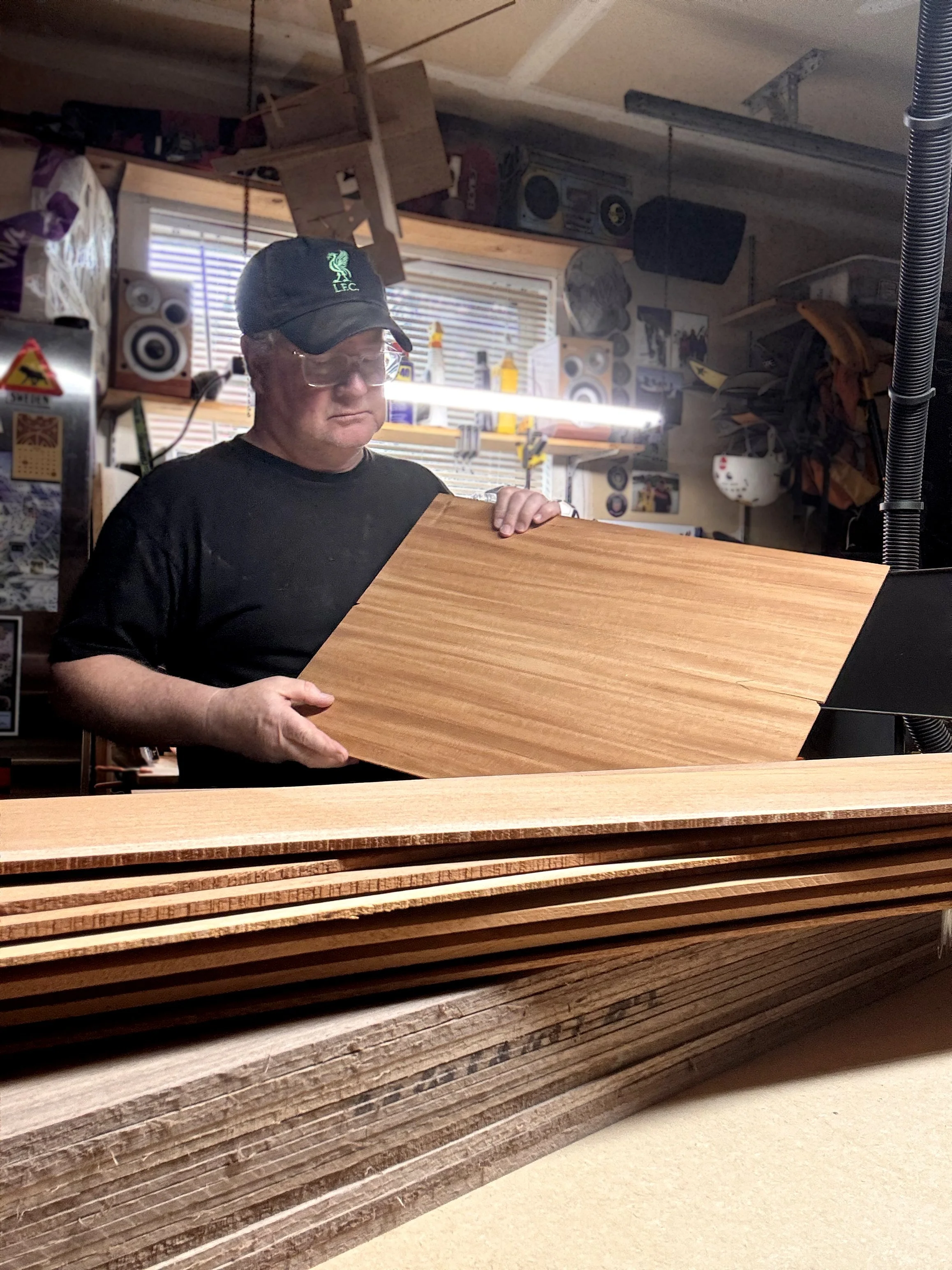 Artist holding a piece of wood in a woodworking shop.