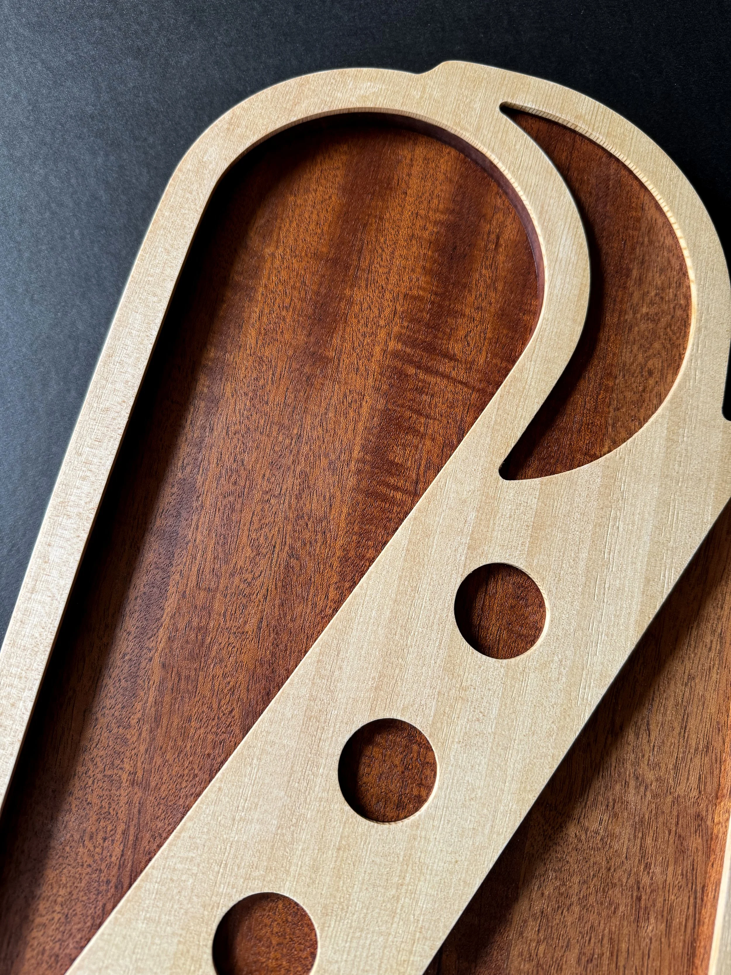 Close-up of a wooden tray handcrafted with circular and curved cutouts and details.