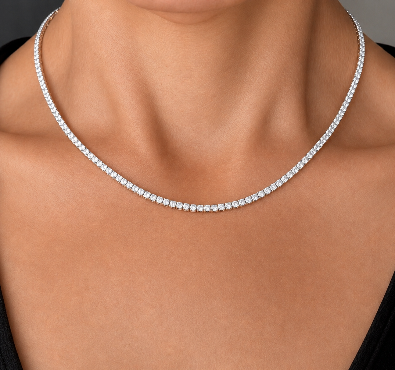 Close-up of a woman's neck and collarbone wearing a diamond necklace.