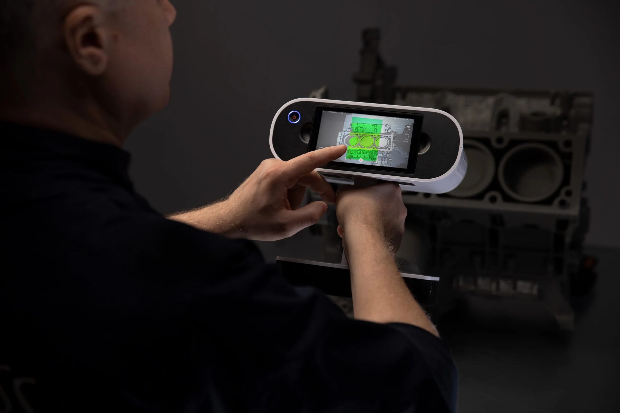 Person holding and using a calibration device with a touchscreen, aimed at a large speaker system.