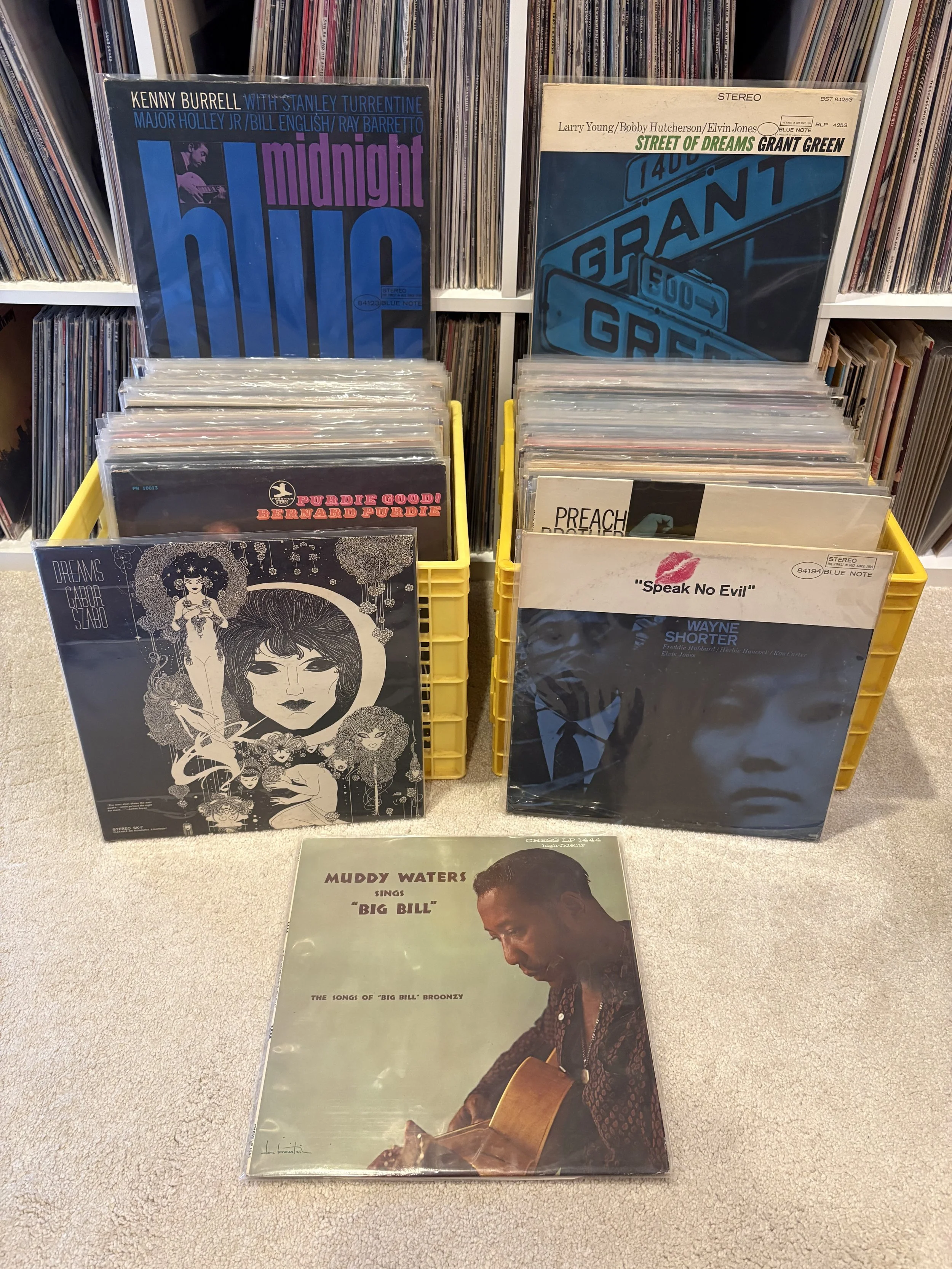 A collection of vintage vinyl records in boxes and racks, featuring jazz, soul, and blues album covers with prominent artists' images and bold typography.