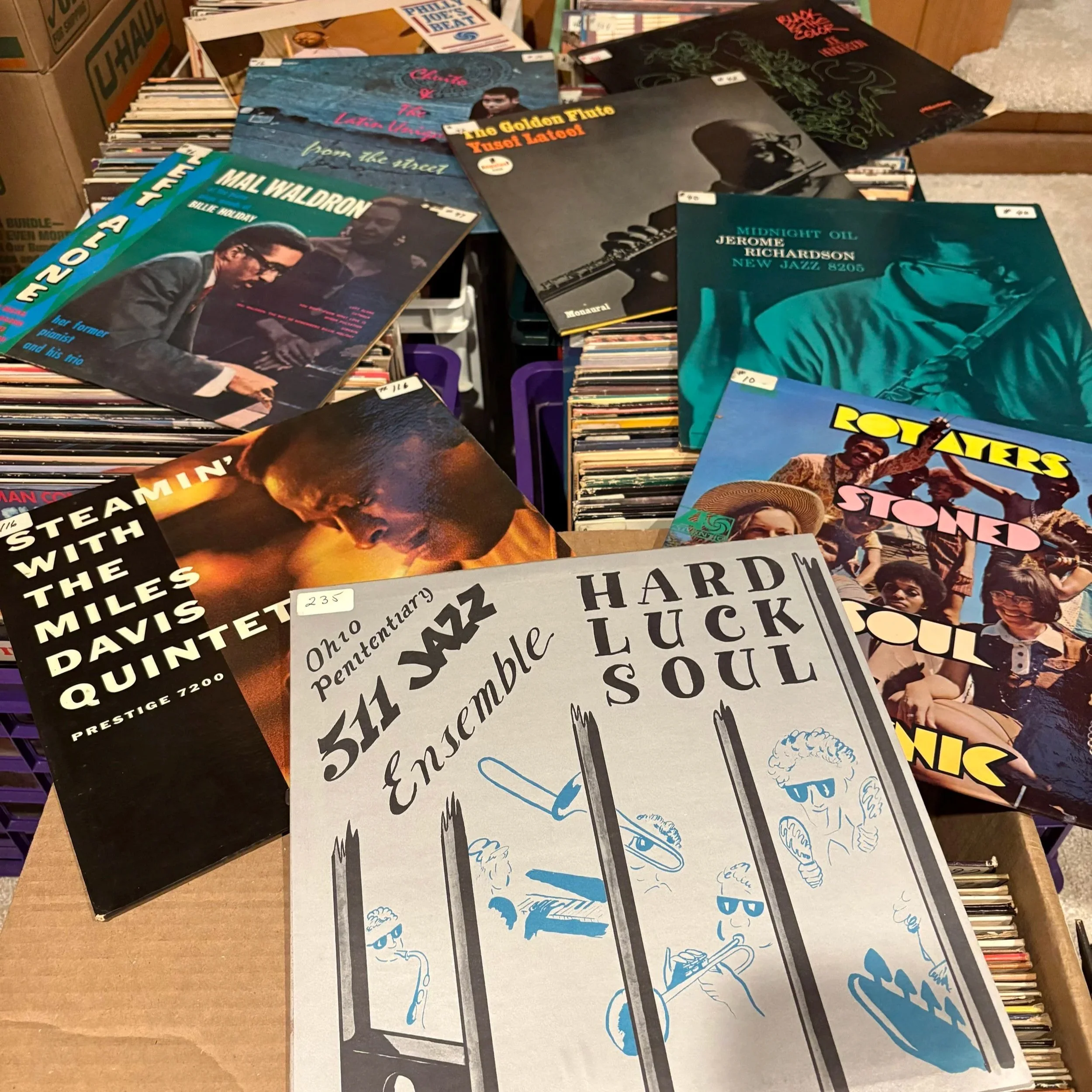 A collection of vinyl records and albums displayed on a table, featuring various album covers with colorful, artistic designs.