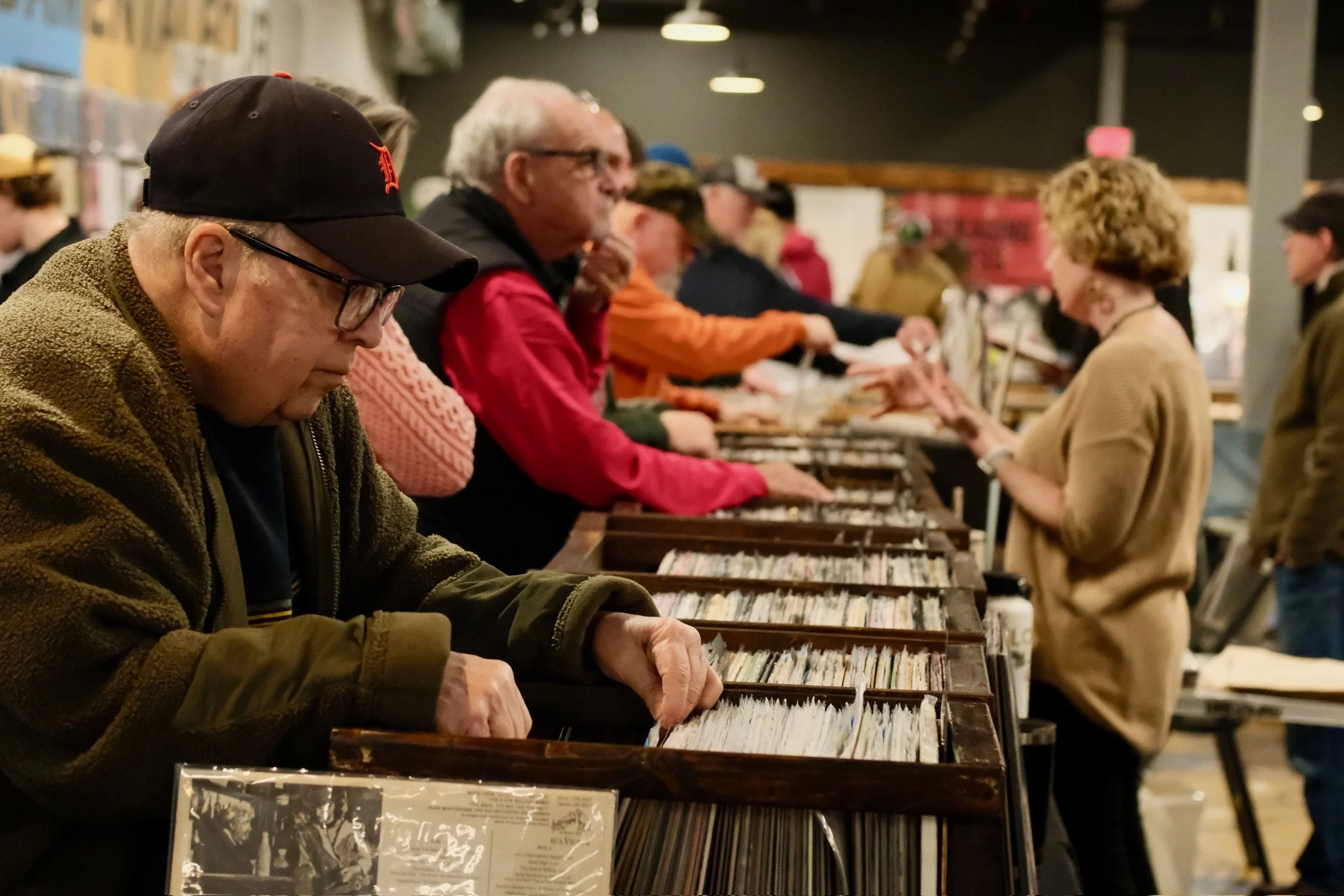 People browsing vinyl records at a music store or event.