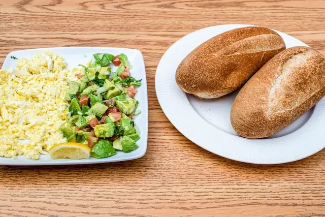Avocado and egg breakfast plate with baby spinach and black pepper