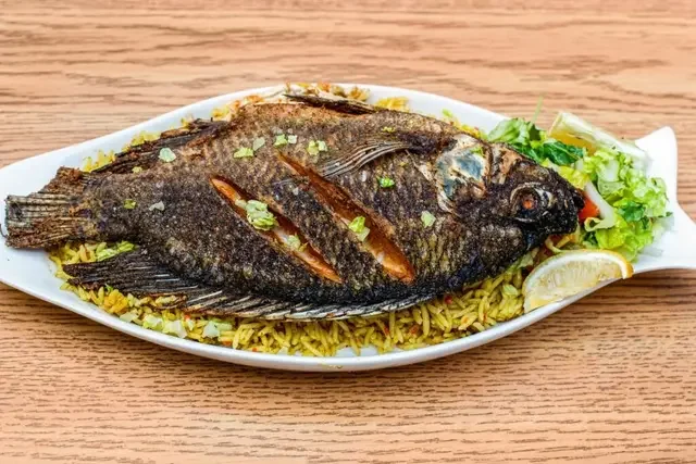 Crispy fried tilapia seasoned with spices served with rice or fries