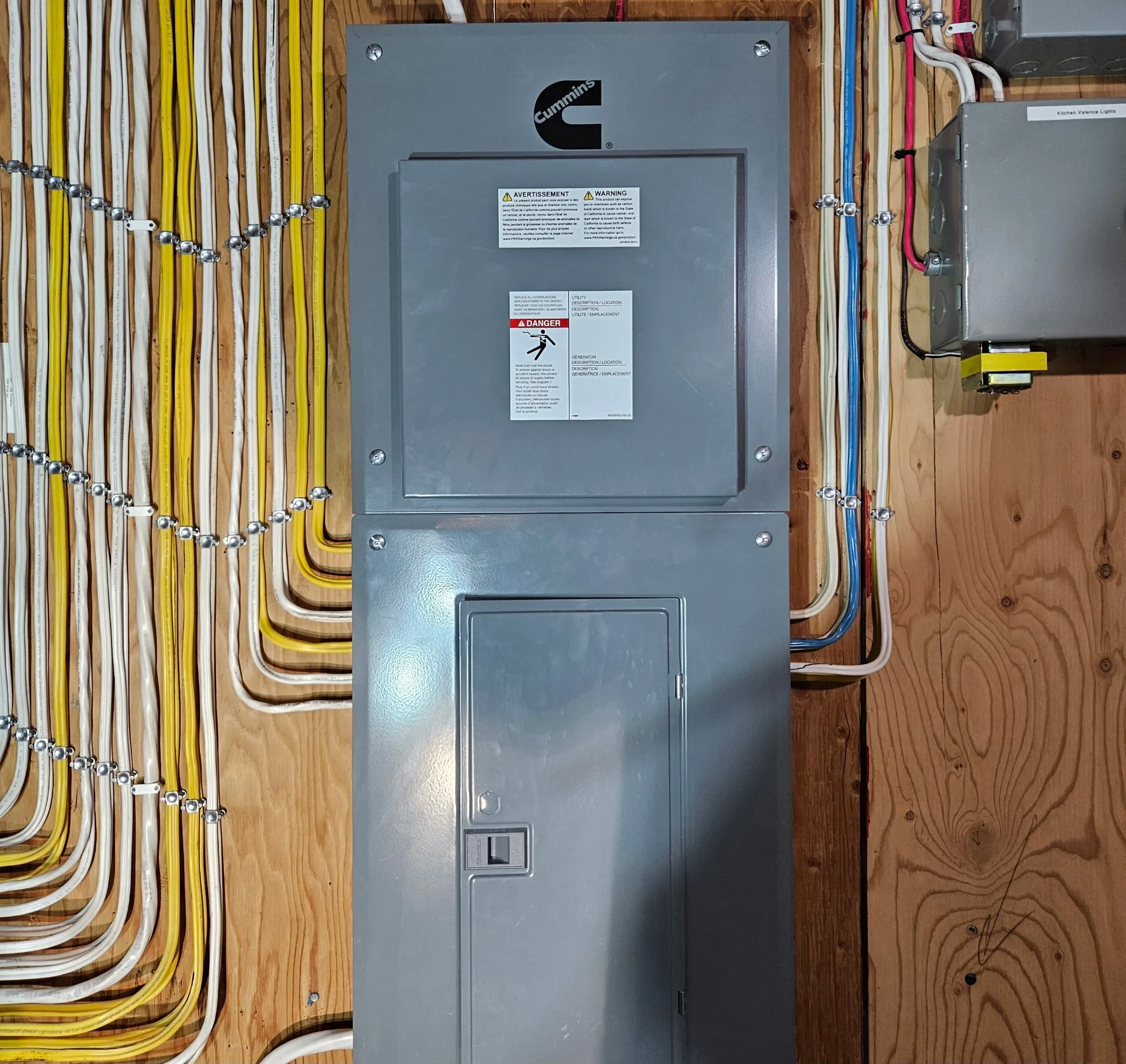 Electrical panel with cables, switches, and wiring on a wooden wall.