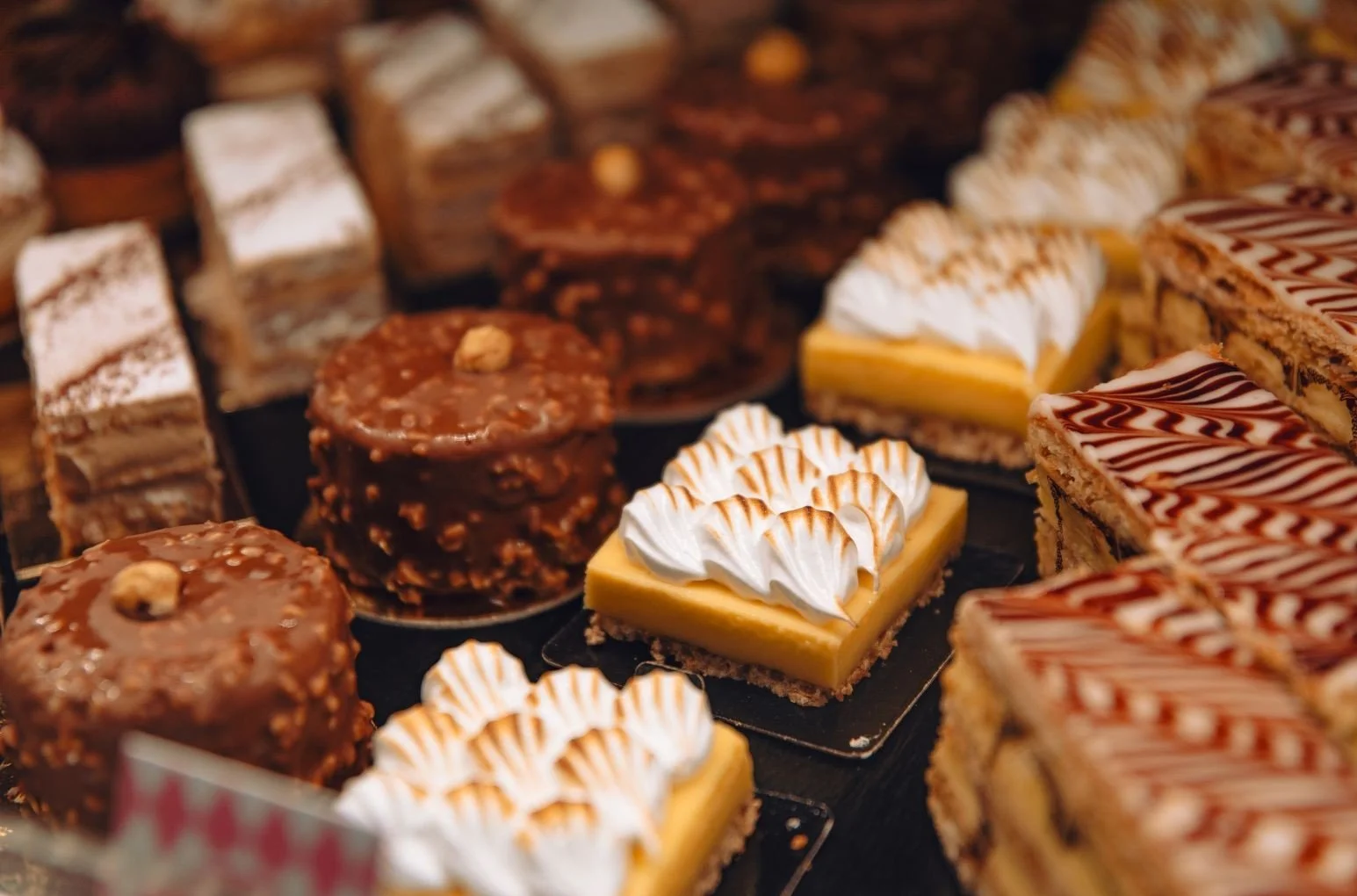 Assorted chocolate and lemon desserts on display, including layered cakes, chocolate truffles, and lemon bars with whipped cream.