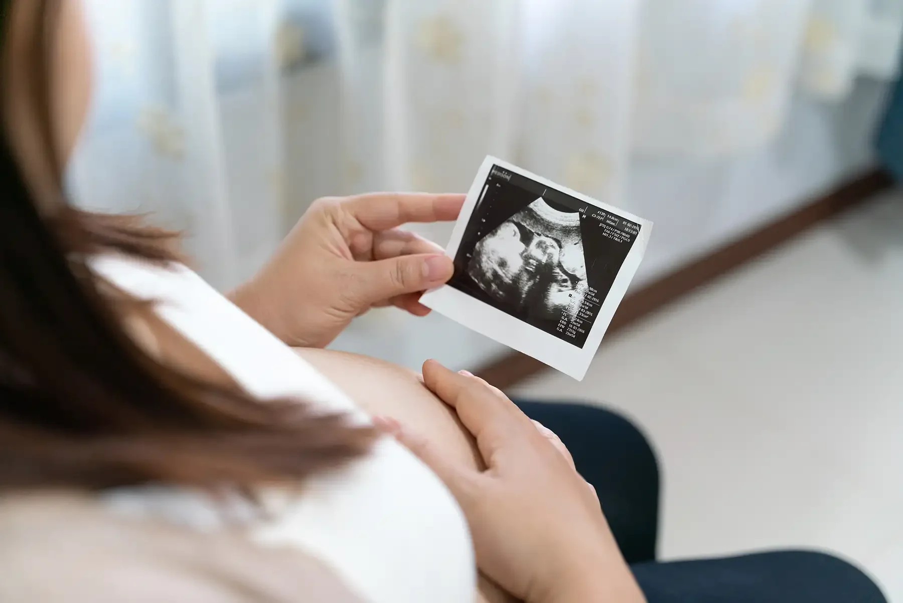 a lady holding an ultrasound of her child in one hand with other hand on her stomach