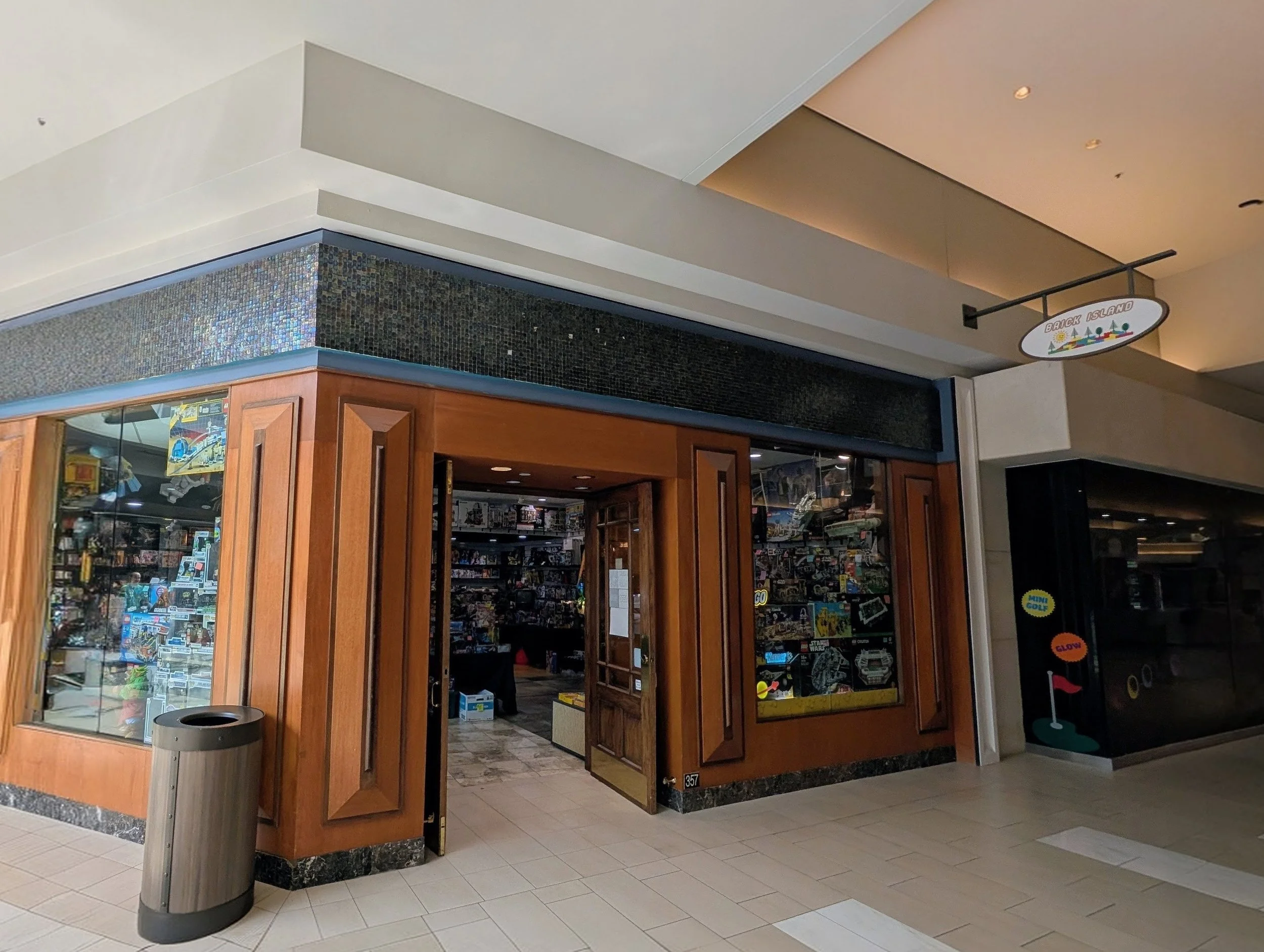 A store in a shopping mall with glass display cases, wood framing, and a sign overhead reading 'Brick Island'.