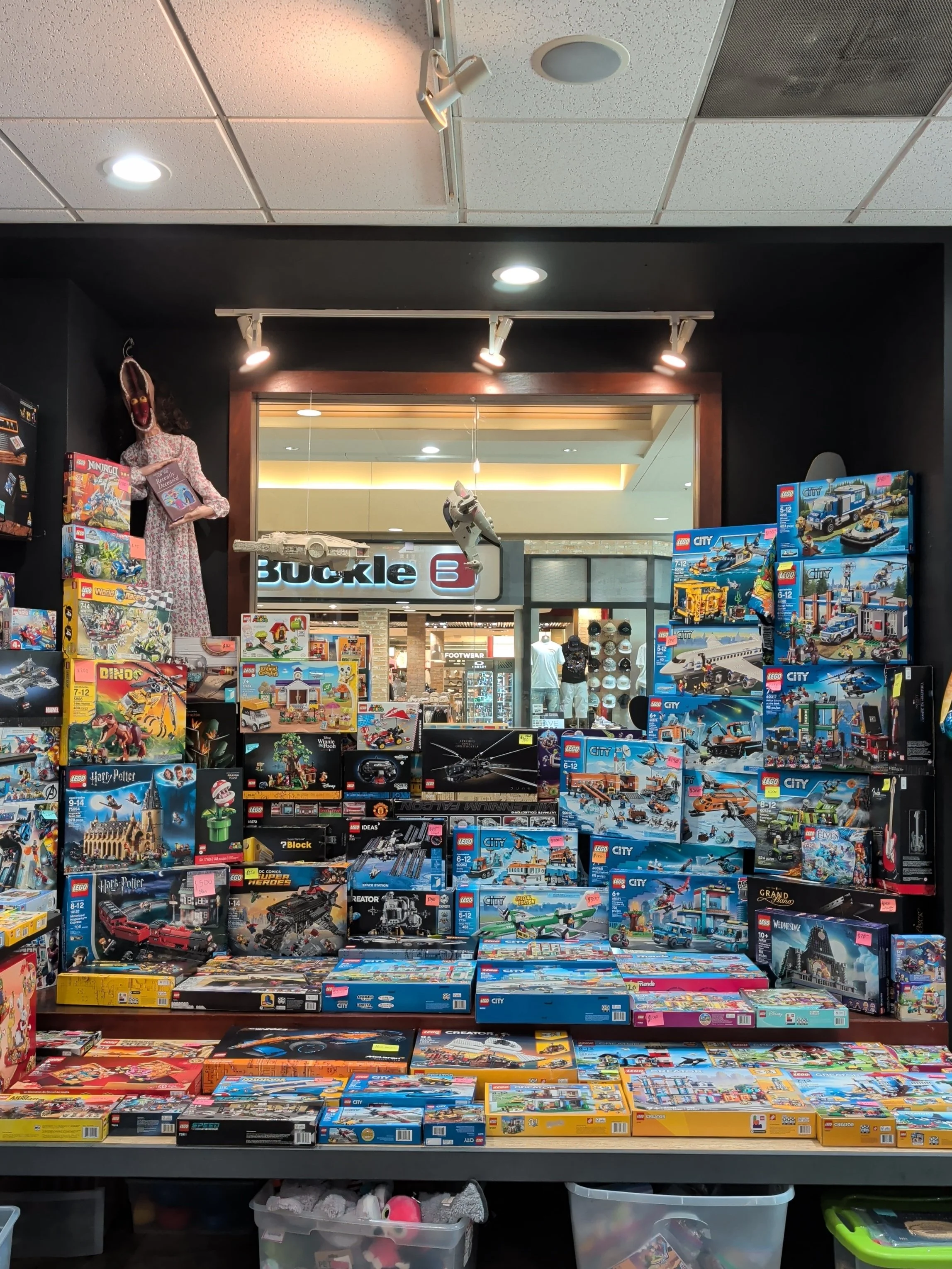 Display of LEGO sets and toys in a store, with a variety of box designs featuring vehicles, characters, and scenes from popular franchises.